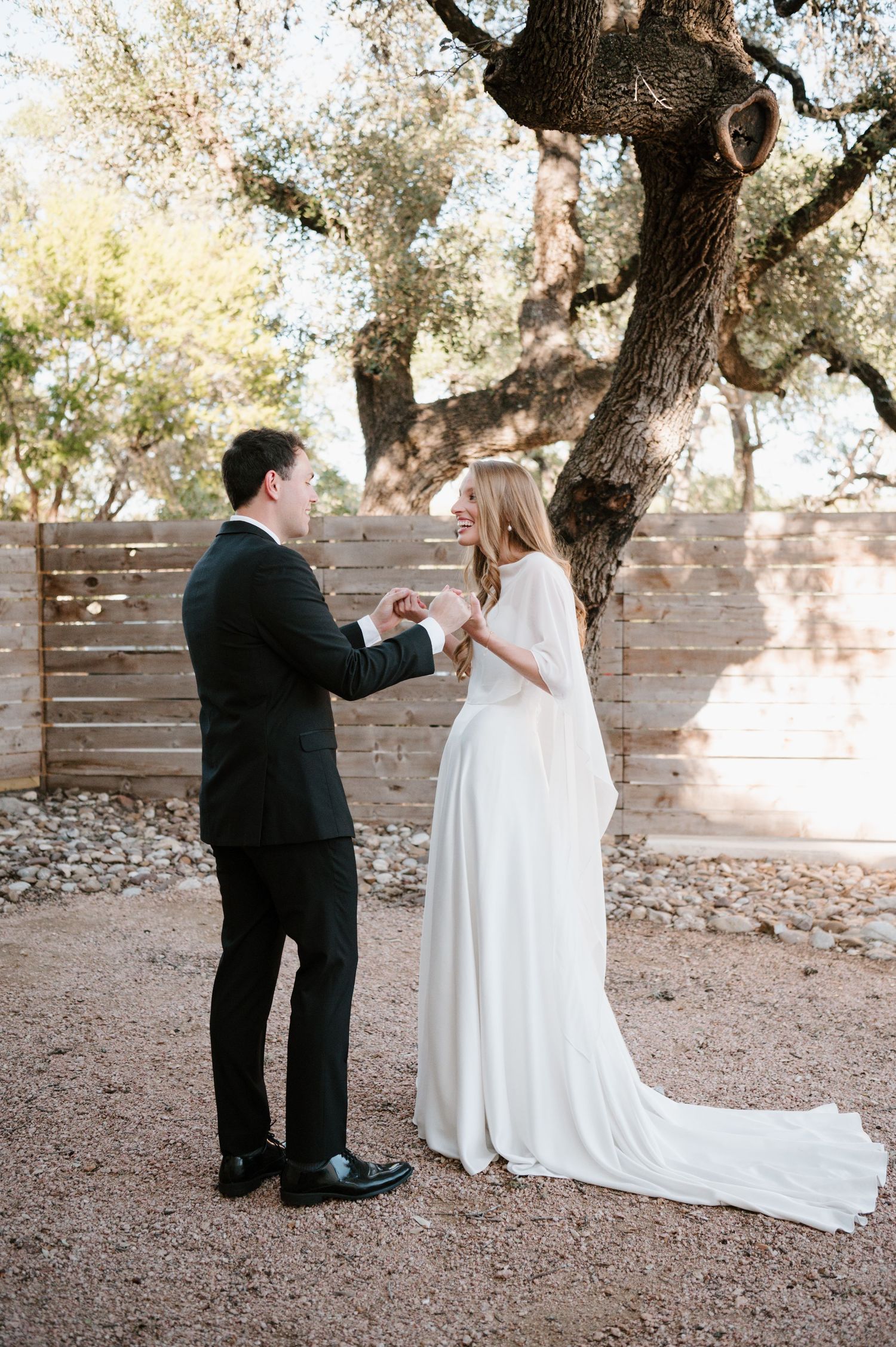 A couple shares an intimate moment under a rustic olive tree during their outdoor wedding ceremony.