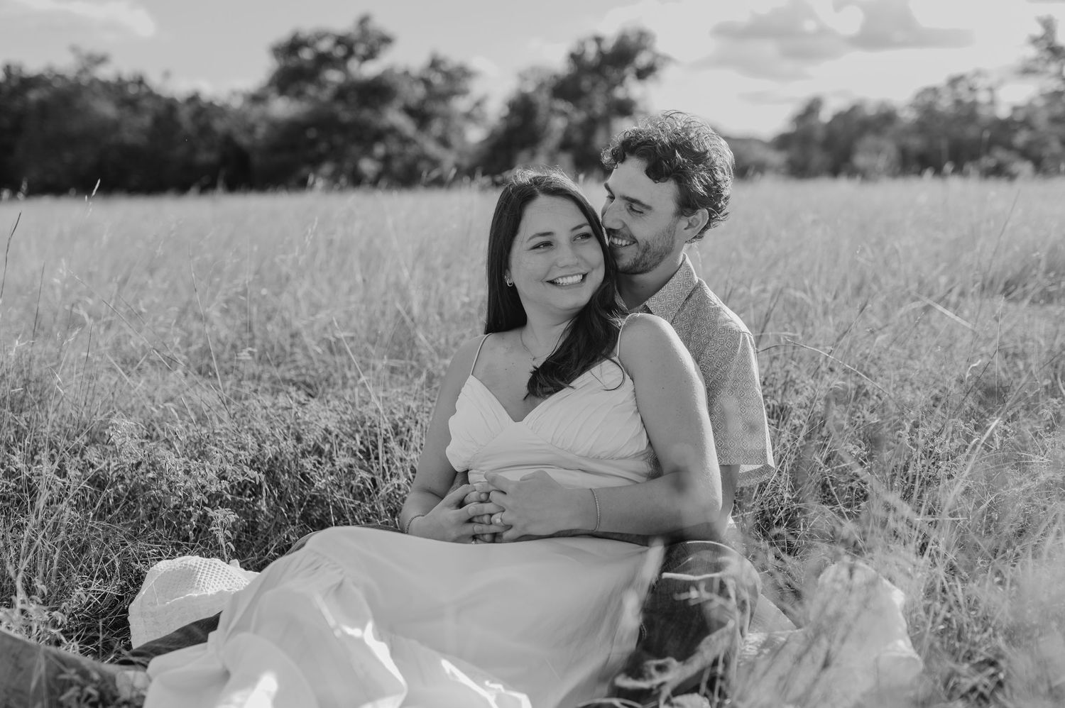 A couple embraces lovingly in a sunlit meadow during a romantic outdoor photo session.