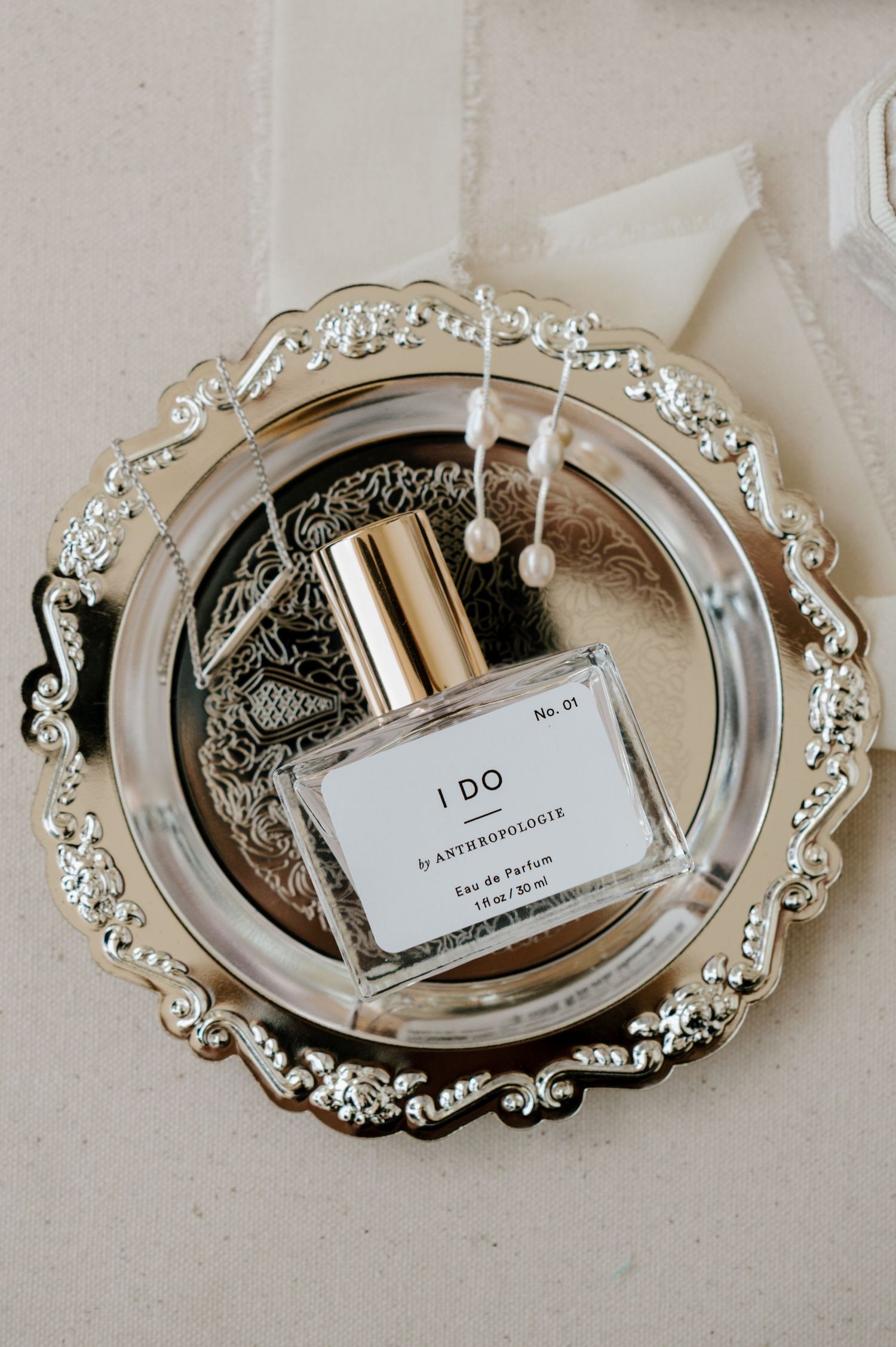 Perfume bottles and wedding accessories arranged on ornate silver trays.