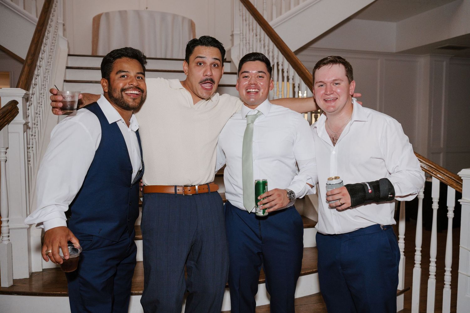 A group of groomsmen celebrating and posing together at a wedding reception.