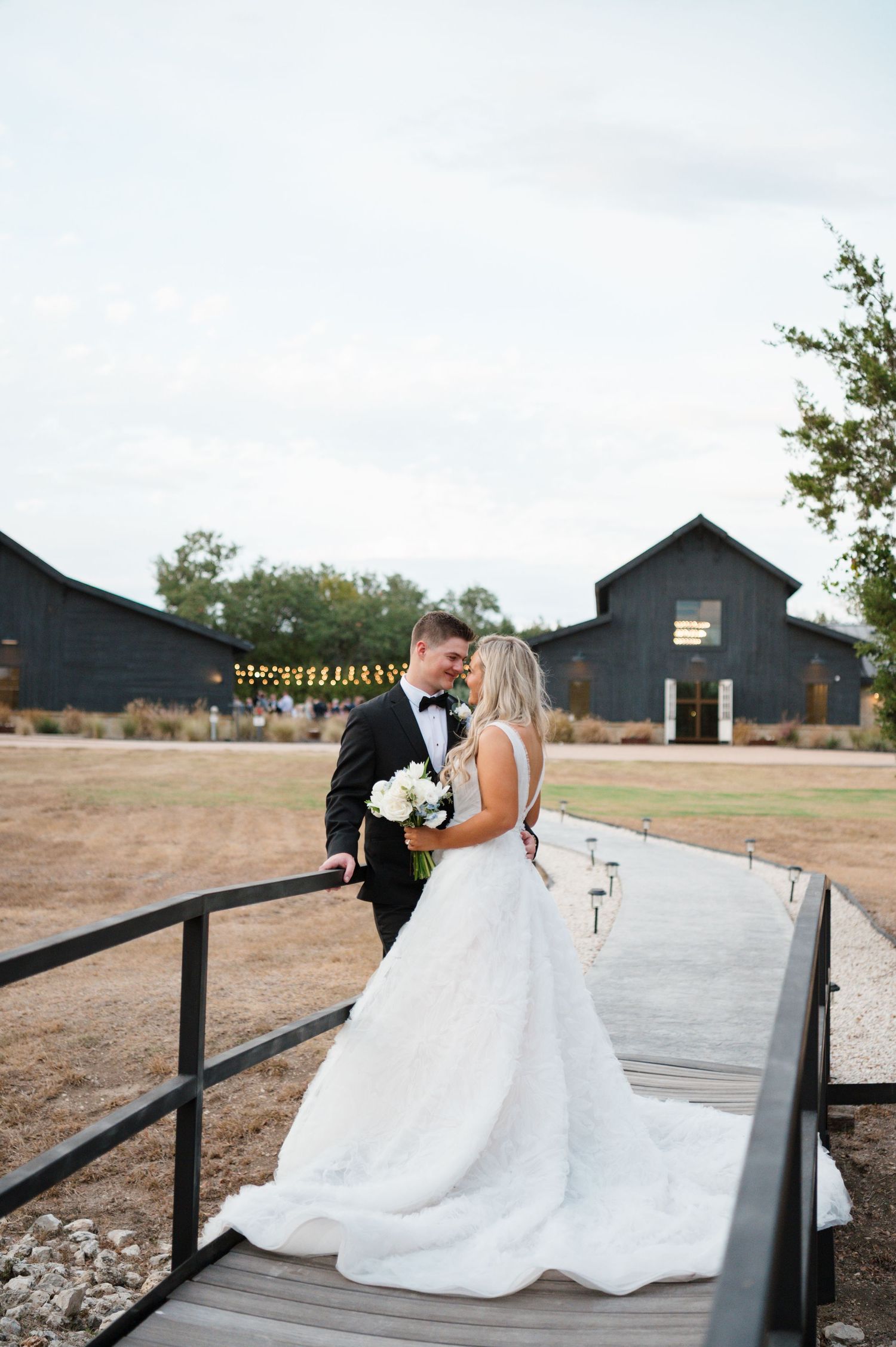 A bride and groom posing for a photo in a rustic outdoor setting.