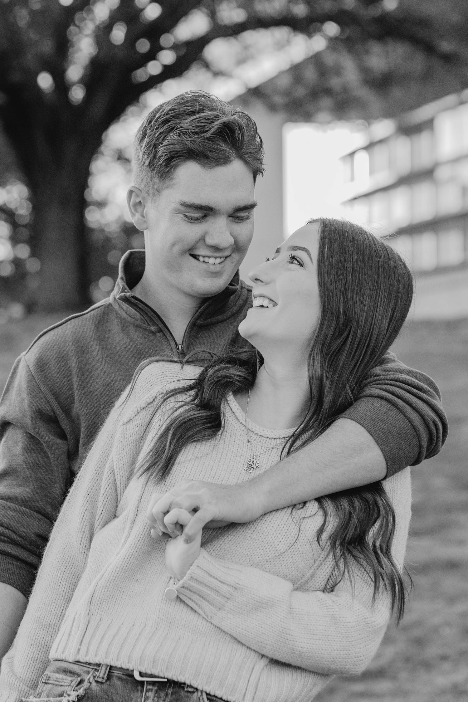 A black and white portrait of a couple sharing an intimate moment outdoors.