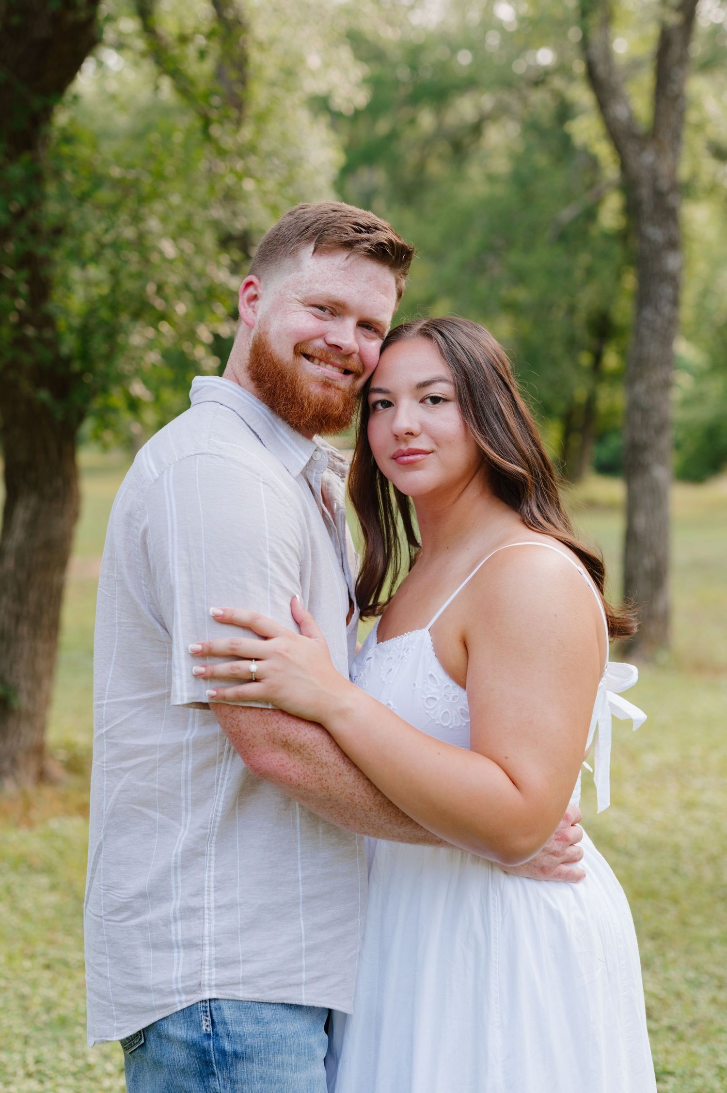 A loving couple shares intimate embraces in a natural outdoor setting with trees in the background.