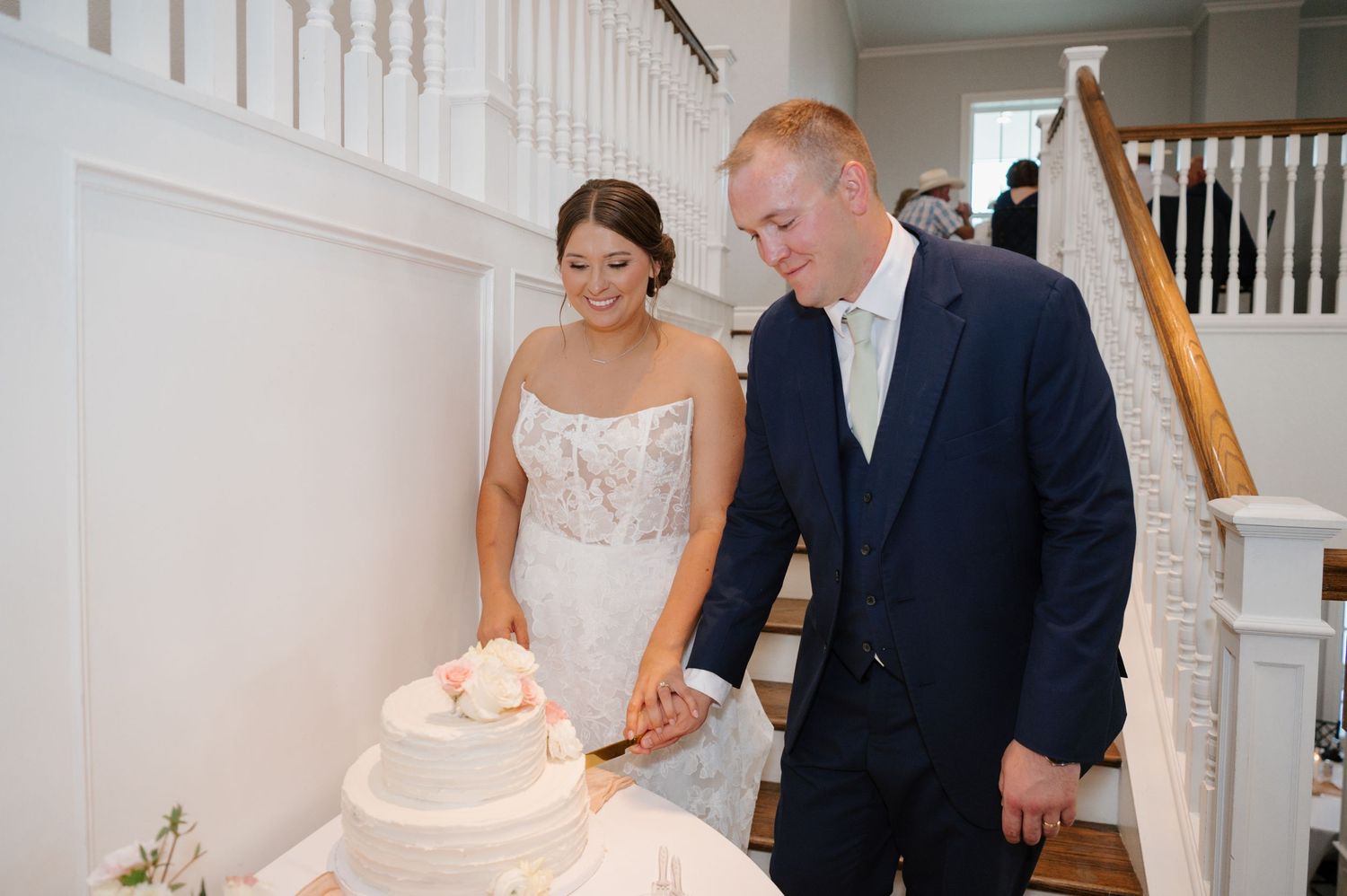 Newlyweds cutting their classic white wedding cake at the reception.