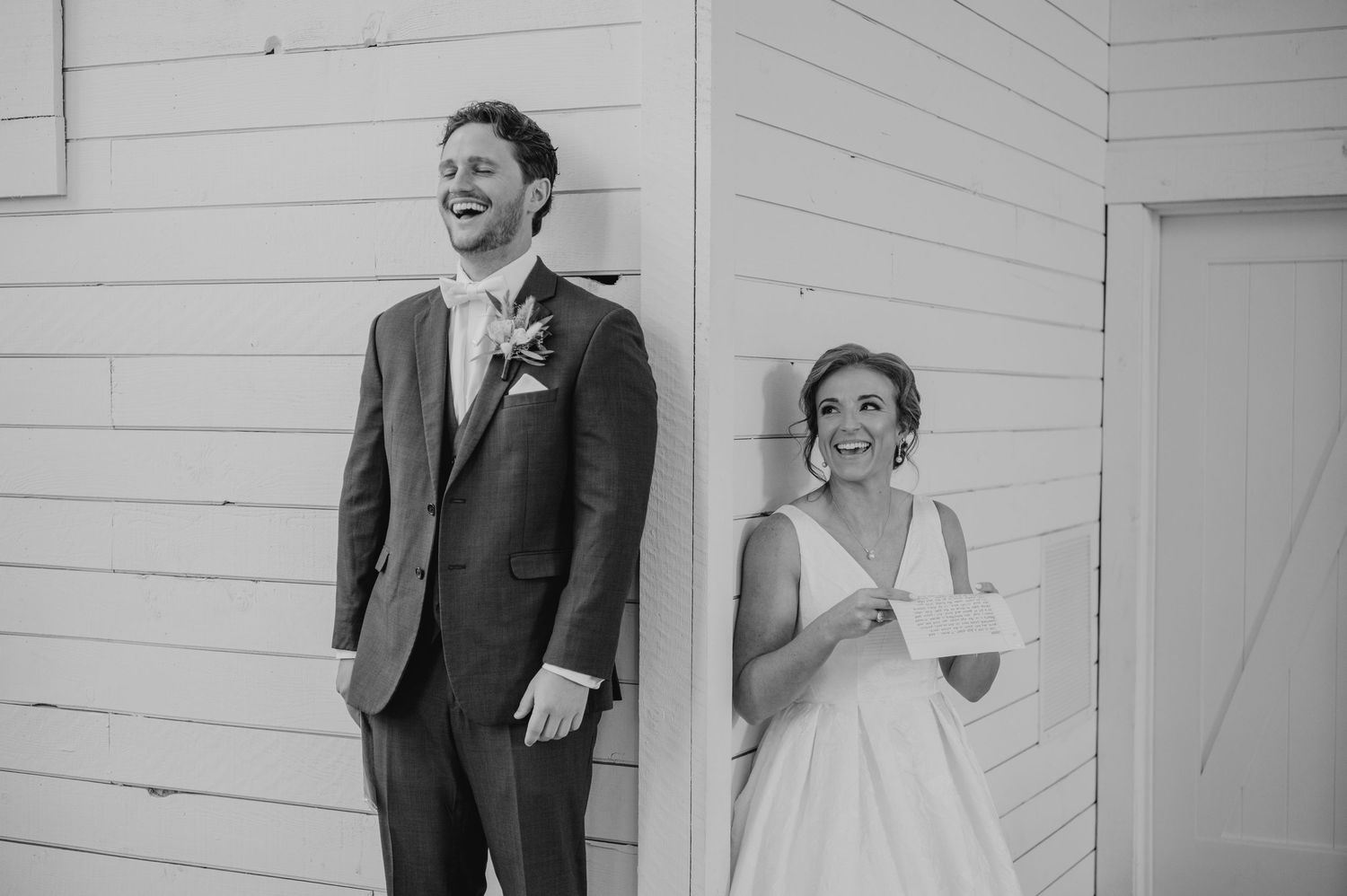A joyful moment captured in black and white at a wedding celebration with guests reacting with laughter.