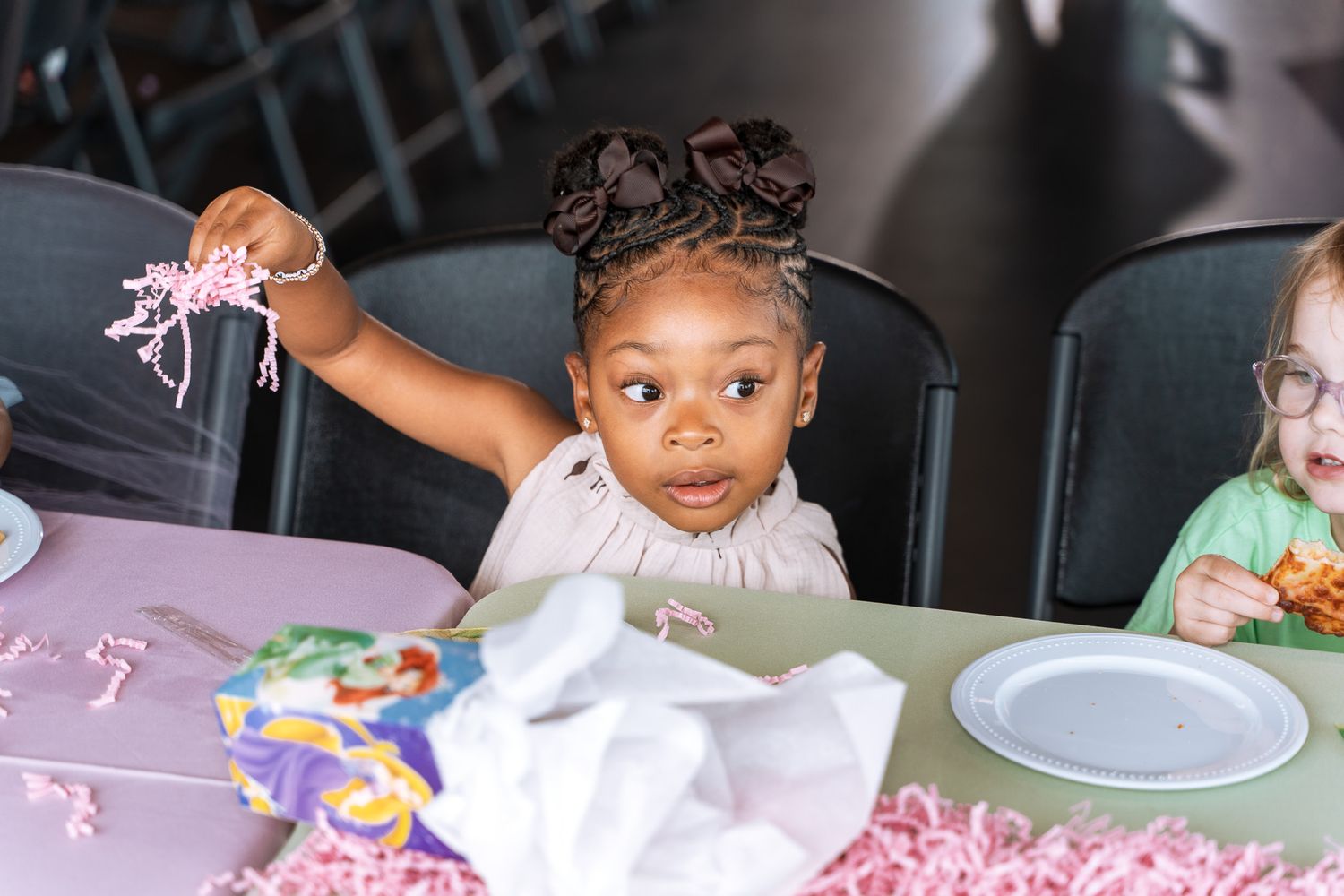 Young party guest enjoying refreshments at decorated pink table.