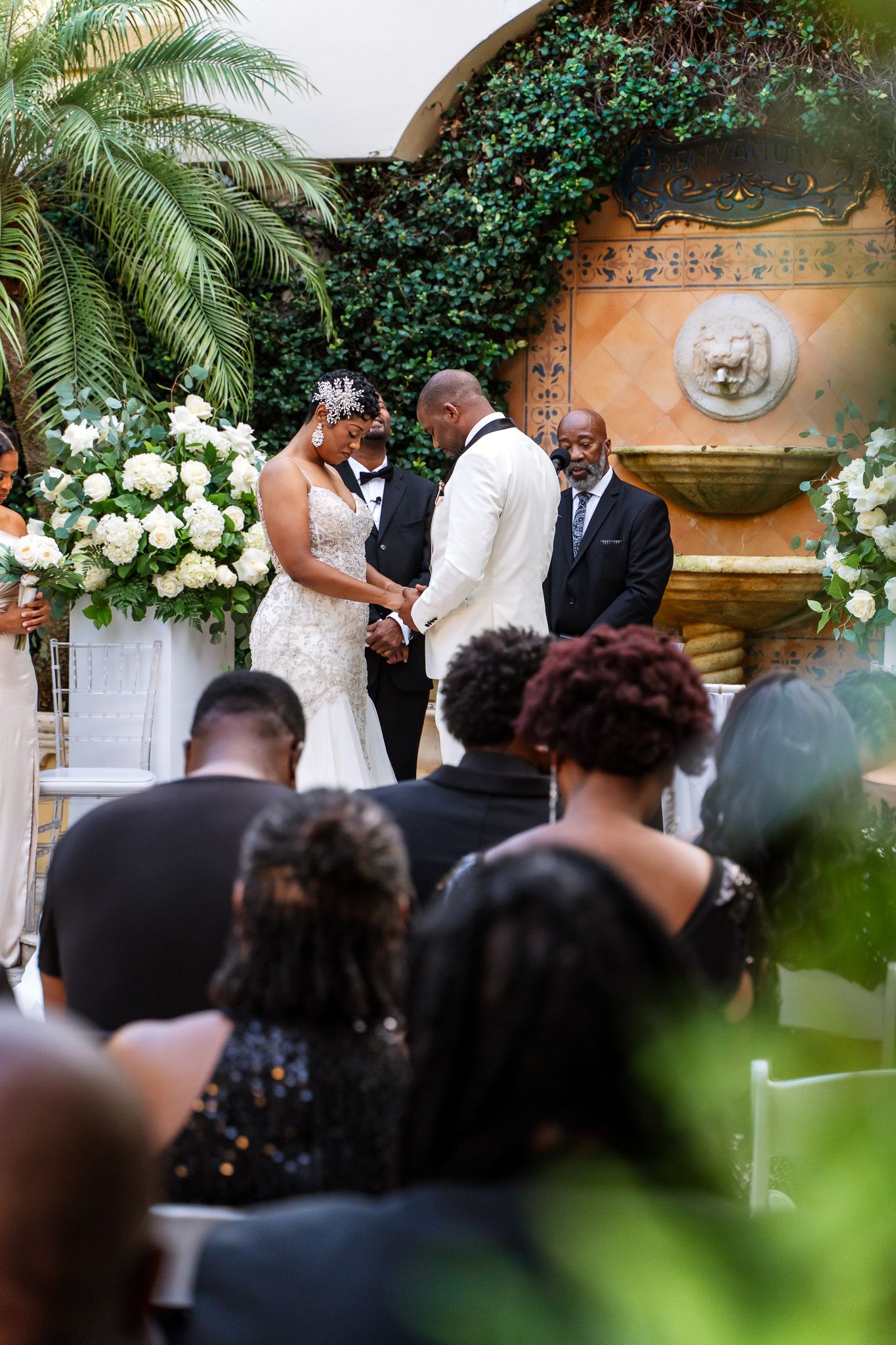 Intimate wedding ceremony moment in a tropical garden setting with guests looking on.
