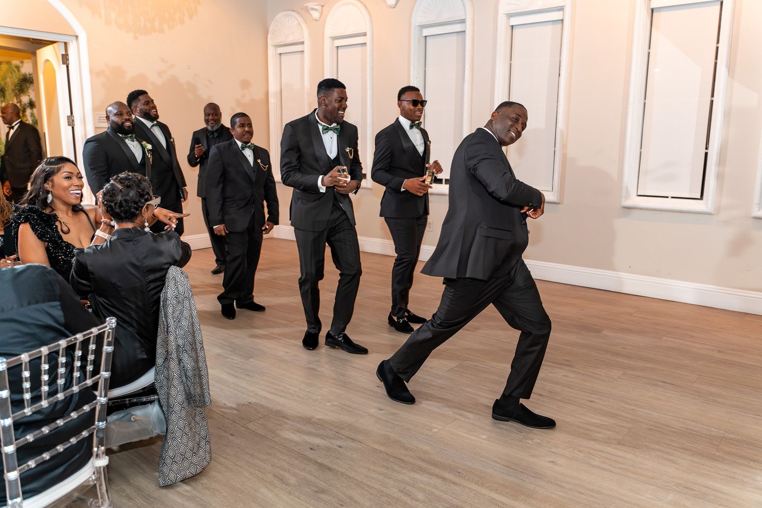 Wedding guests dancing energetically on a wooden dance floor at an elegant reception venue.