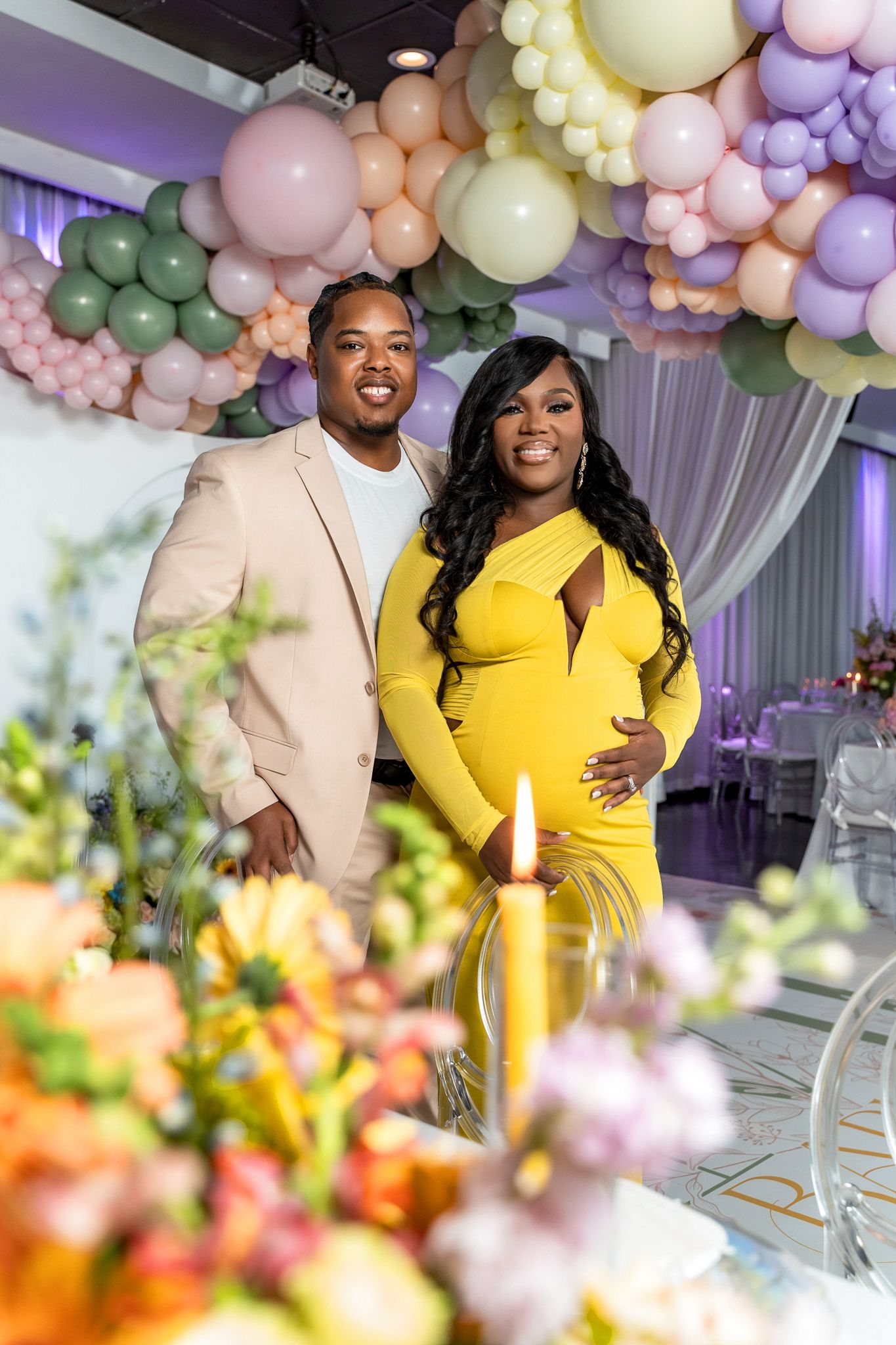 A celebration under pastel balloon arches with floral decorations in an elegant venue.