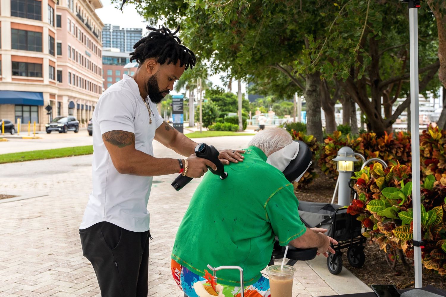Two people interacting outdoors near landscaped gardens and buildings.