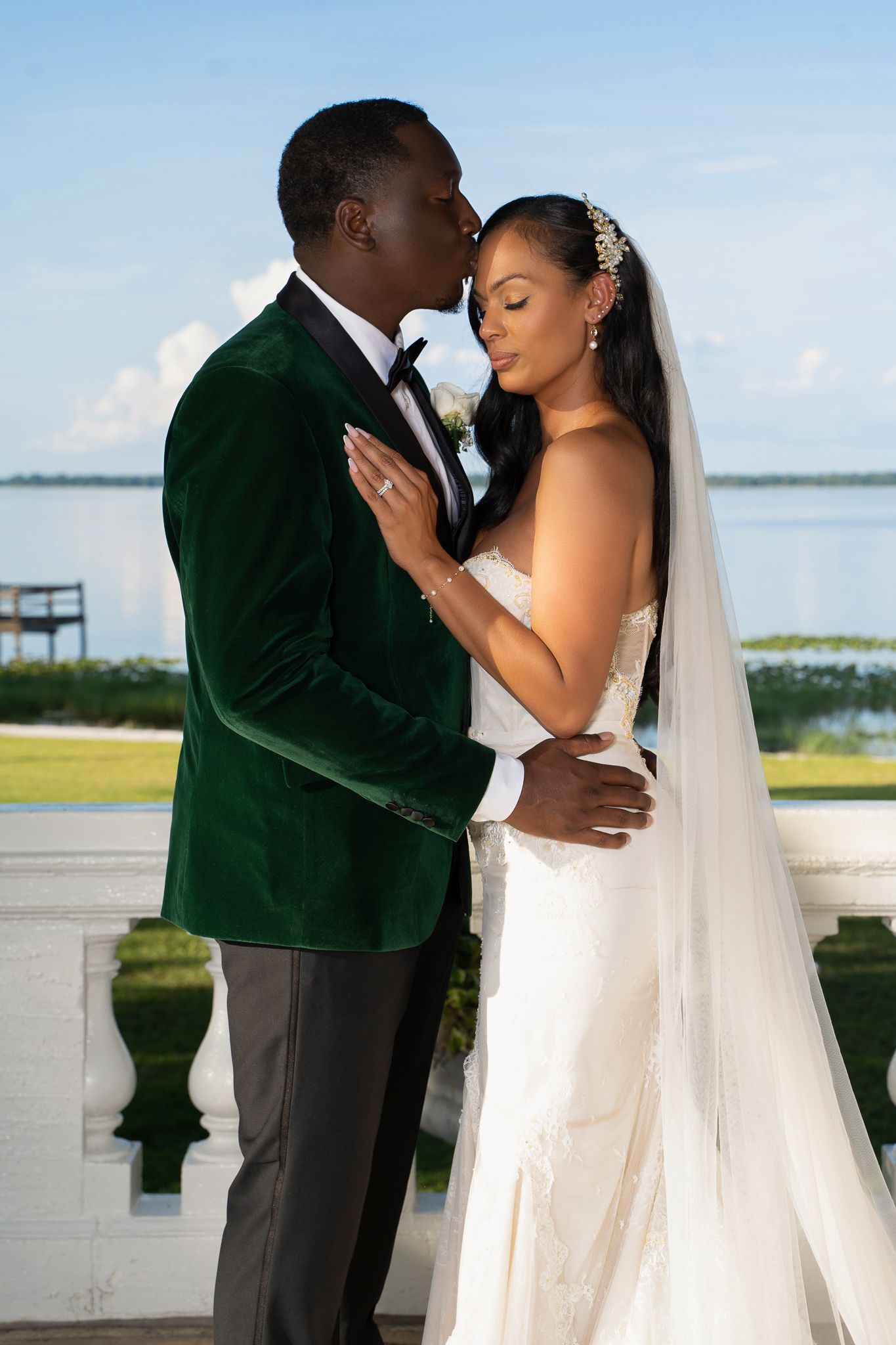A tender moment between newlyweds in front of a waterfront backdrop.
