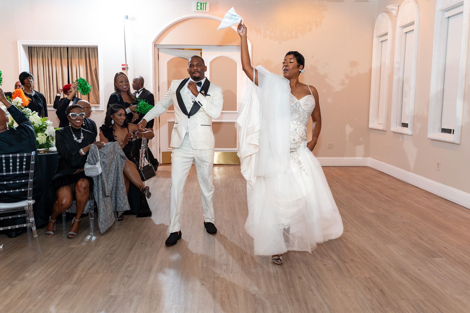 A joyous wedding celebration moment with guests cheering during a reception dance.