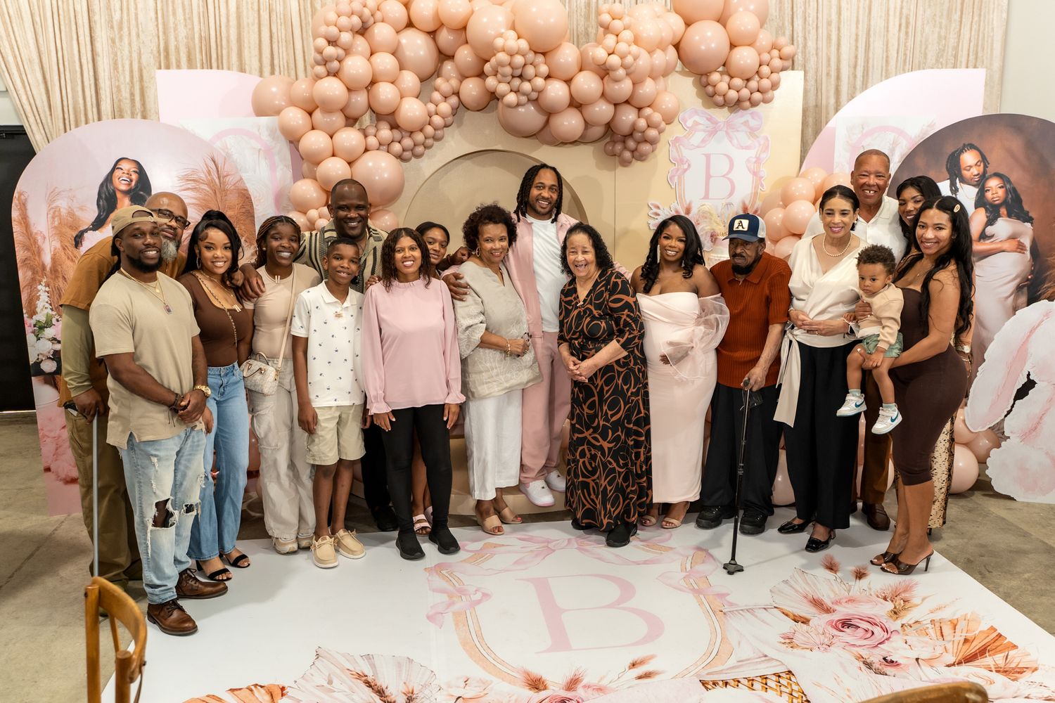 Large group photo of celebration attendees posing together against balloon wall backdrop.