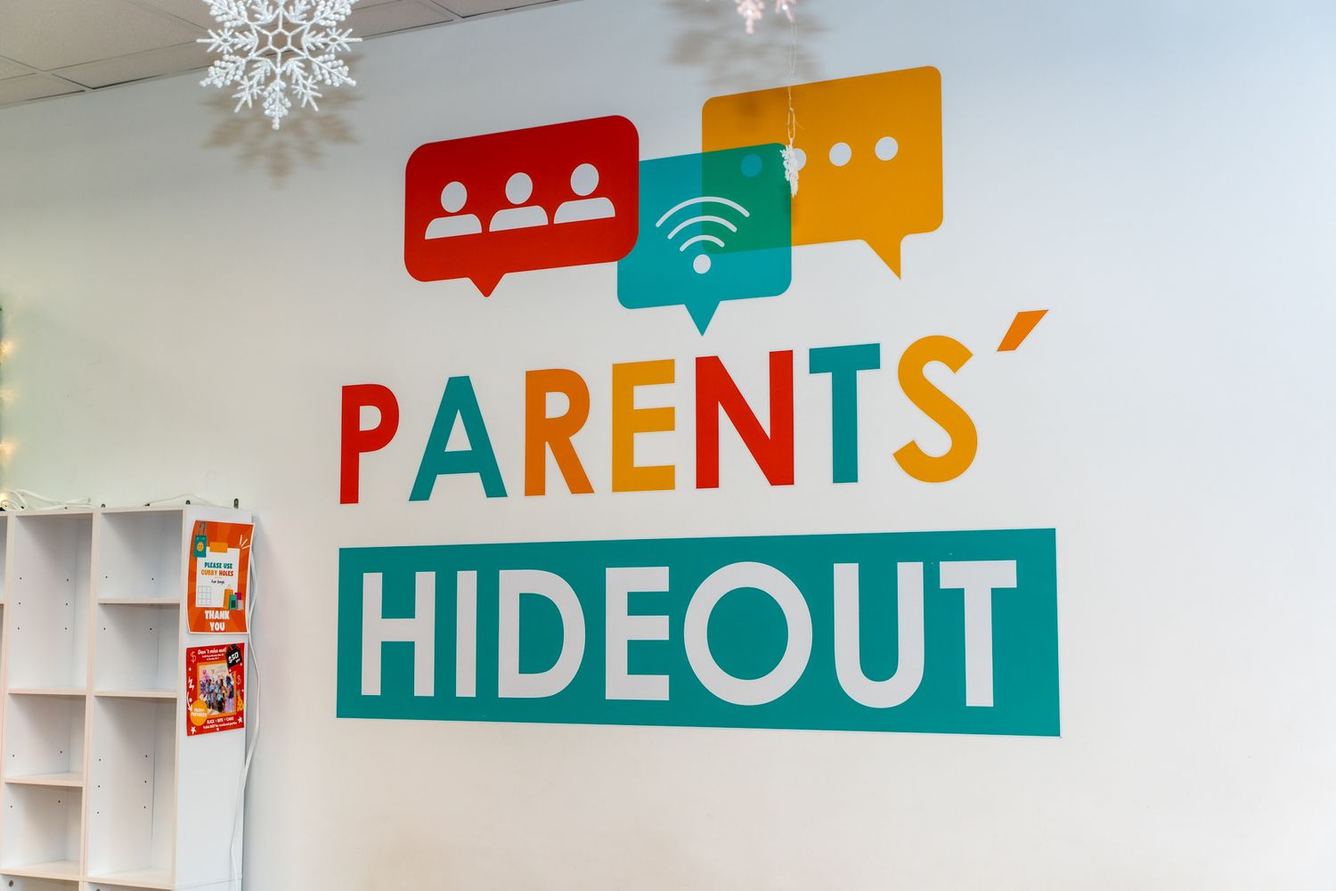 Colorful Parents Hideout sign with speech bubble graphics mounted on white wall.