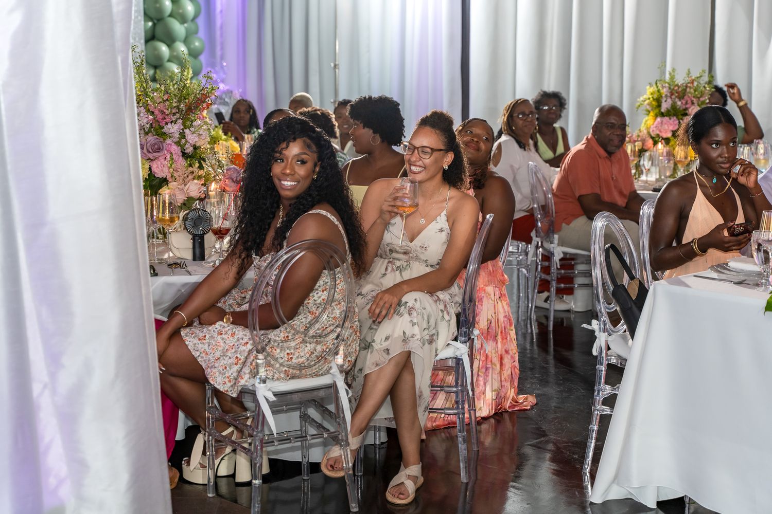 Guests enjoying themselves at elegant tables with clear chairs and white linens.