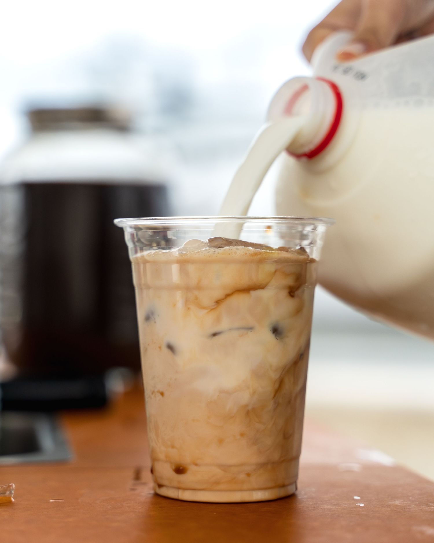 Milk being poured into a glass of iced coffee creating a swirling effect.