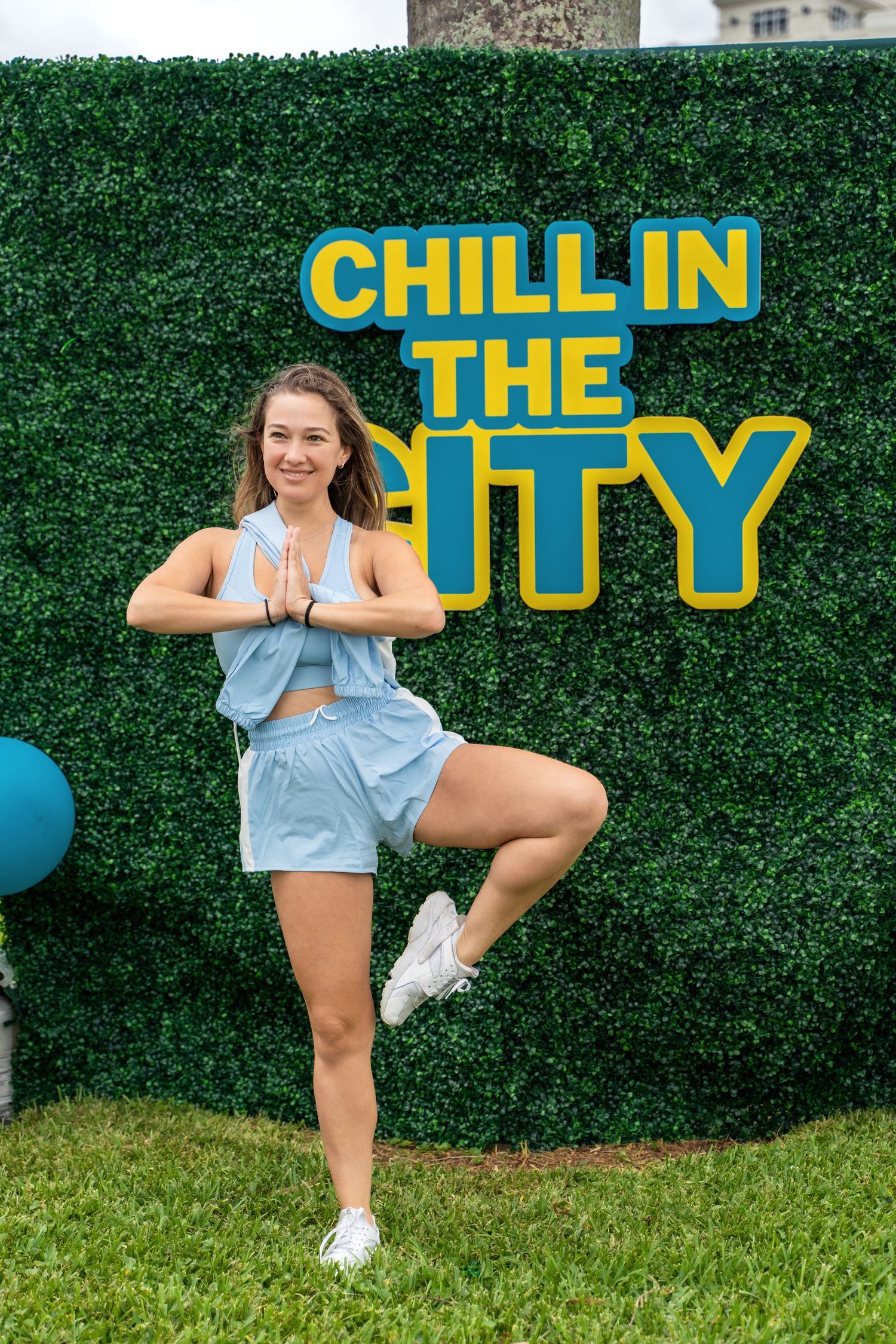 Person striking a yoga pose in front of a green wall with 'Chill in the City' text display.