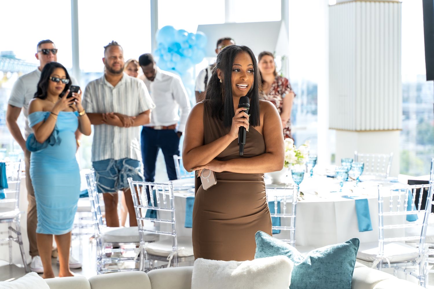 Guest in a brown dress enjoying a celebration in an elegant venue with white chairs.