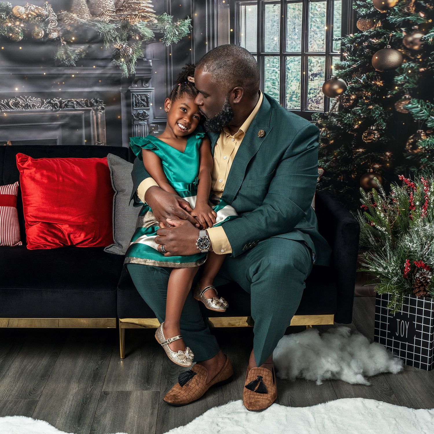 A tender holiday portrait with emerald green and gold formal wear against Christmas decorations.