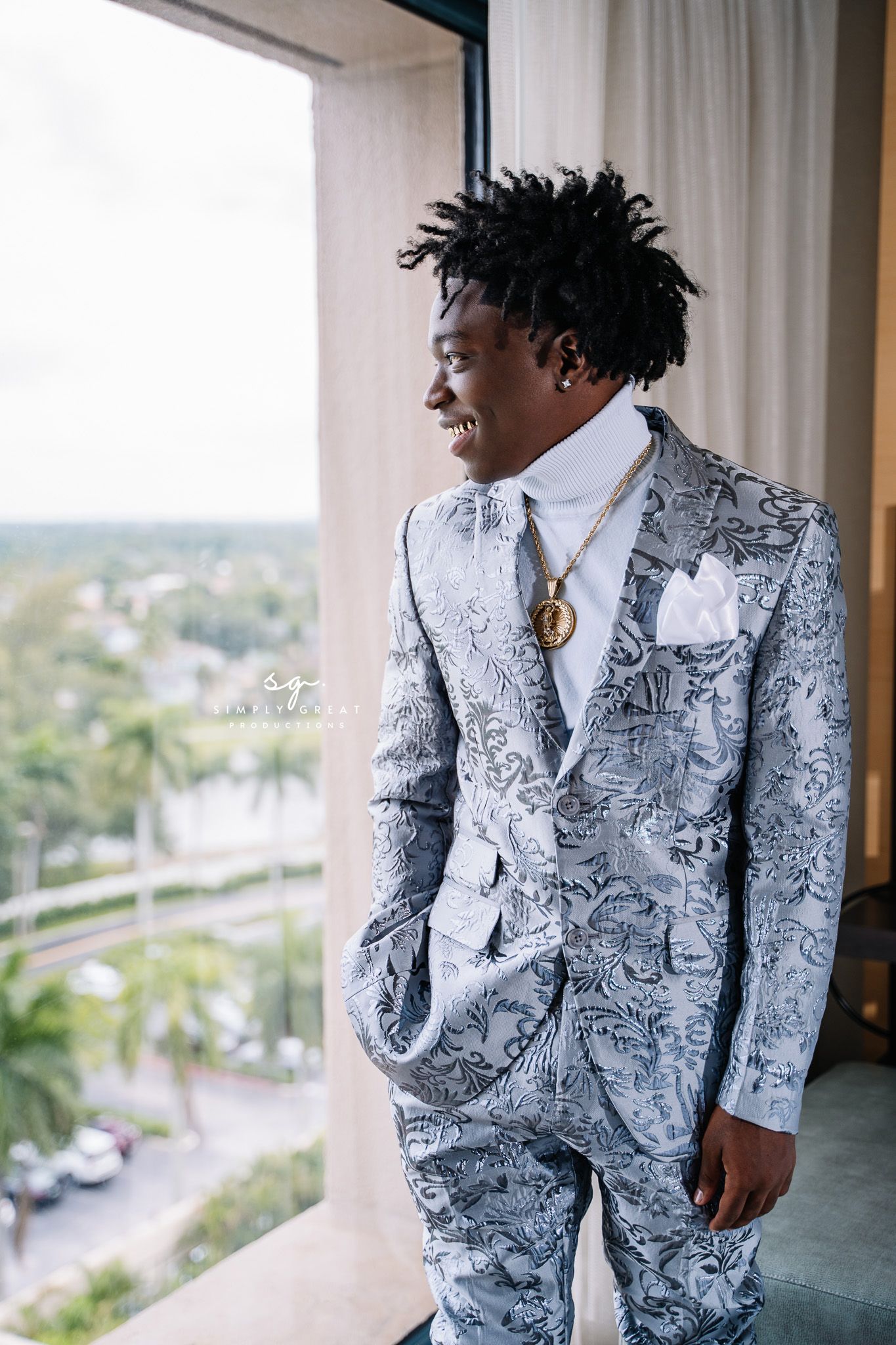 Stylish gray and white patterned suit with botanical motifs photographed against a scenic balcony view.