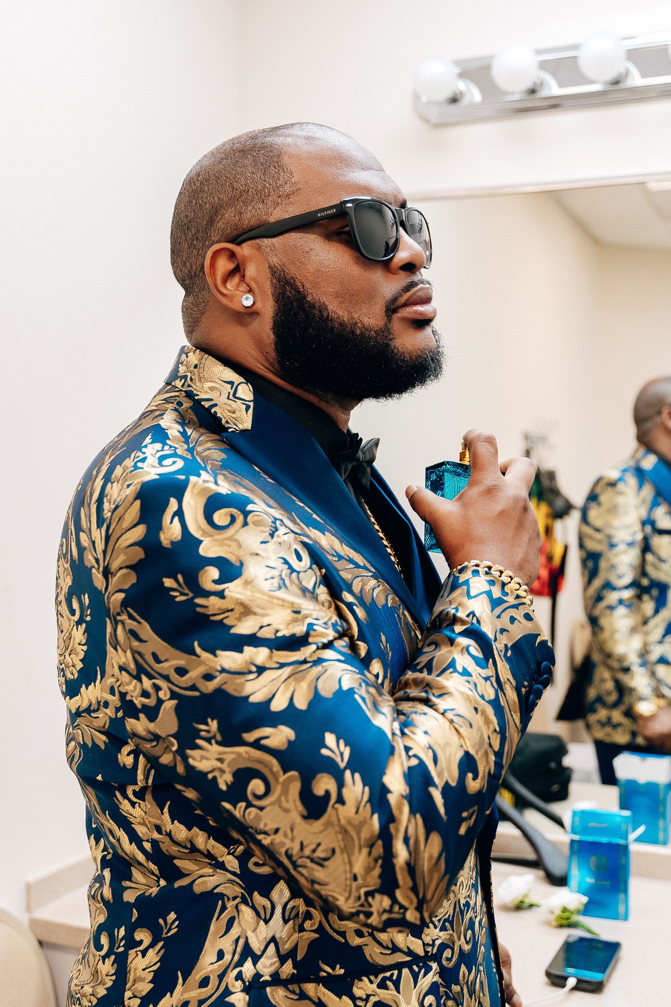 A person wearing a luxurious blue and gold brocade jacket and sunglasses at a formal event.