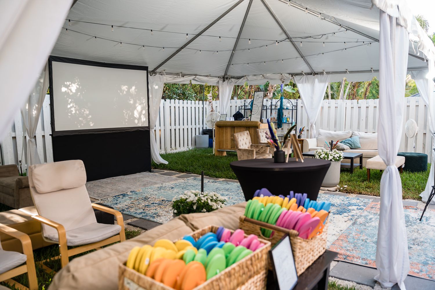 Outdoor tent setup with lounge furniture and colorful pool floats for a party.