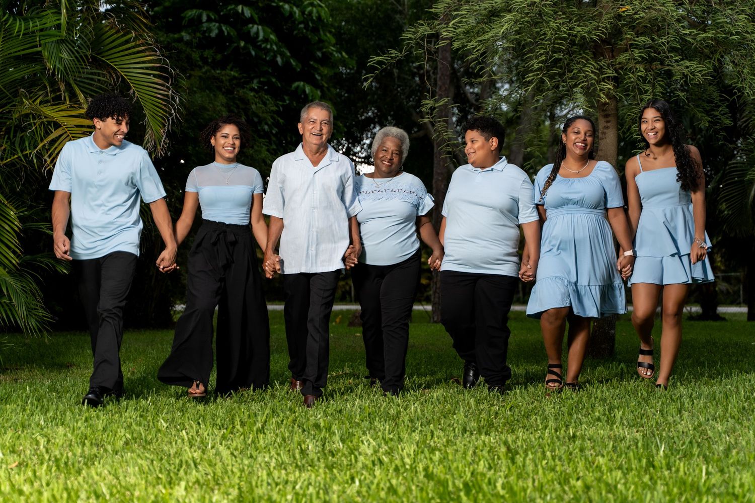 Extended family members arranged in casual poses on grassy lawn wearing matching blue and black attire.