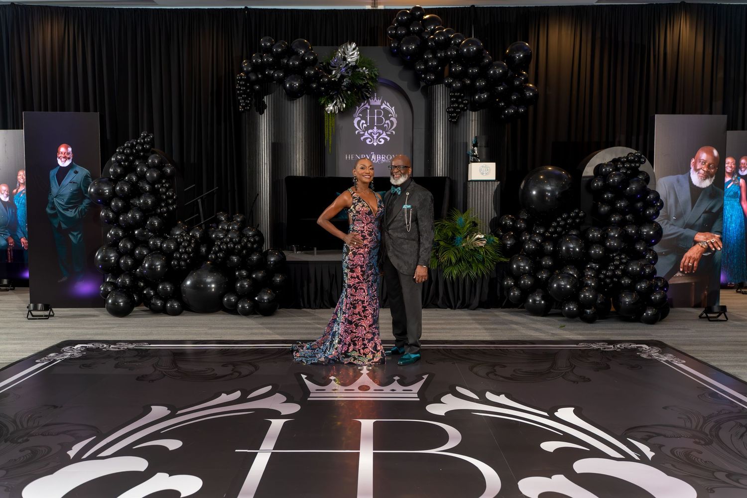 A person in a floral dress performs a dance routine on a black stage with white circular patterns.