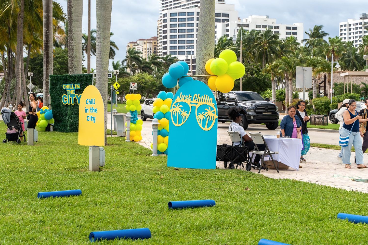 Outdoor wellness event setup with blue yoga mats and promotional displays under palm trees.
