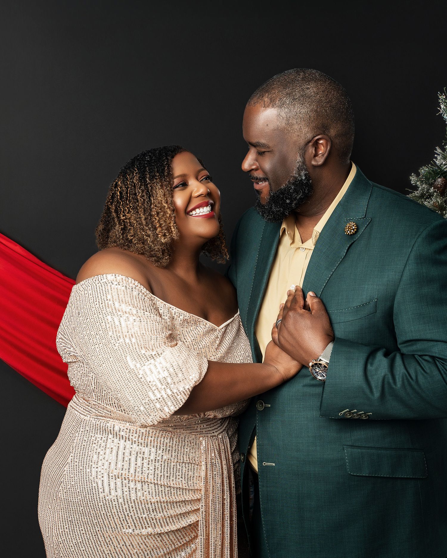 A couple in formal attire share an intimate moment against a dark background.