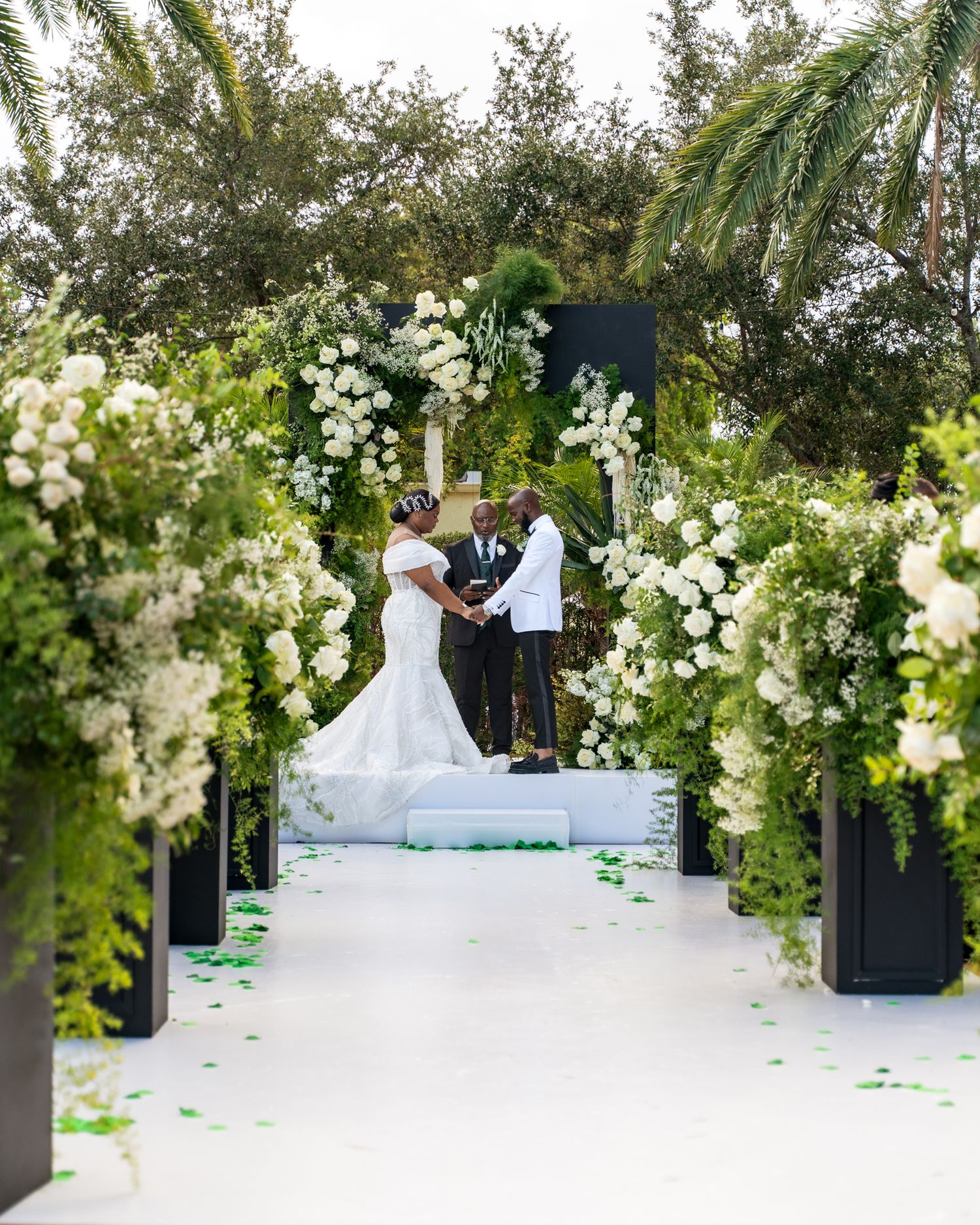 Elegant outdoor wedding ceremony setup with white floral arrangements and green accents creating a romantic atmosphere.