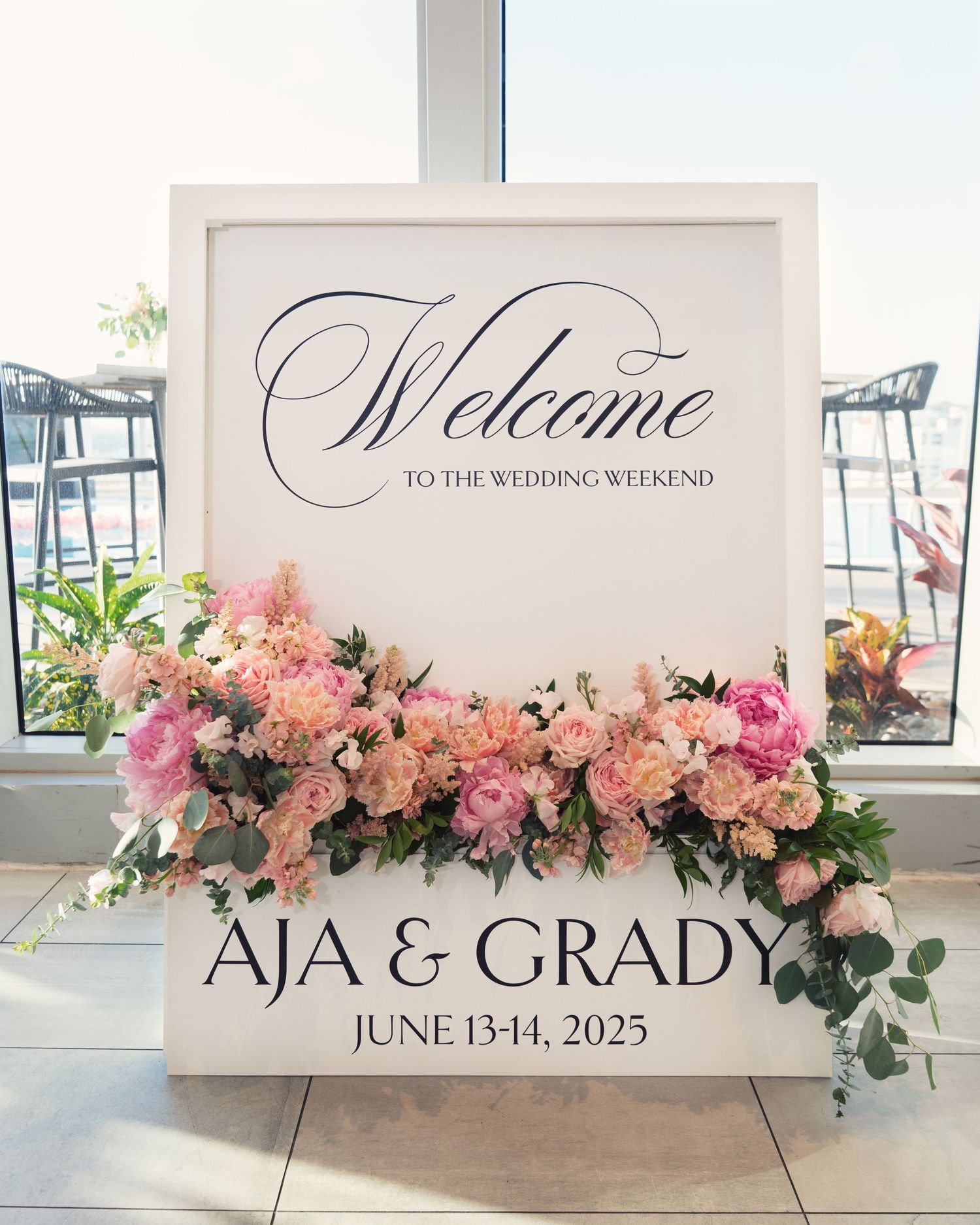 Elegant wedding welcome sign decorated with pink and peach floral arrangements for Aja and Grady's June wedding celebration.