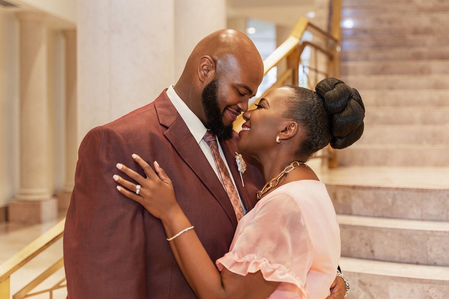 A romantic embrace captured on a marble staircase with gold railings.