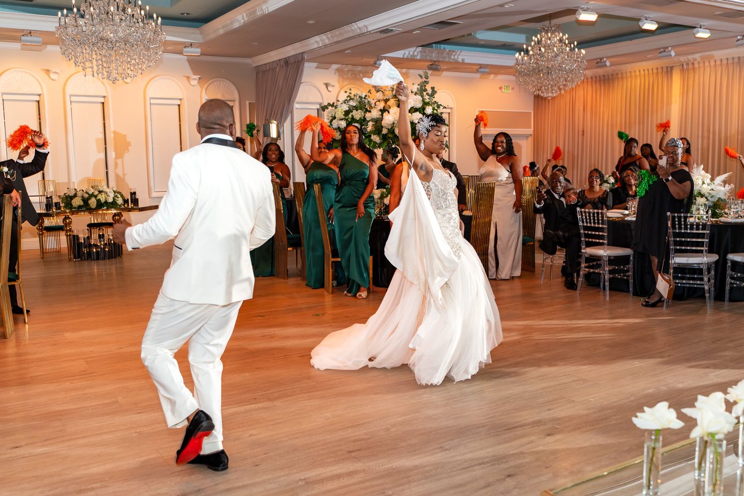 Wedding celebration on a wooden dance floor with elegant decor and chandelier lighting.