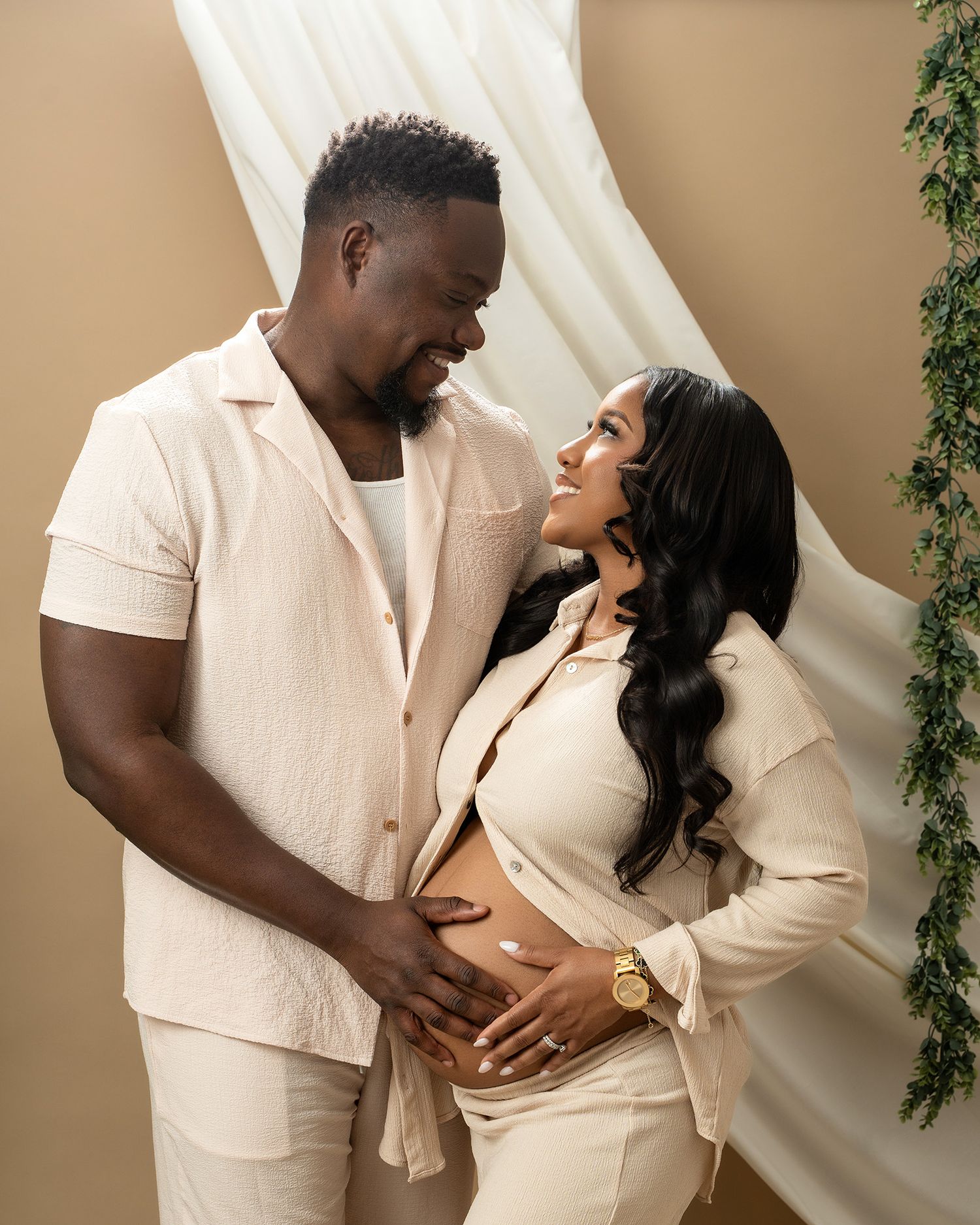 Intimate maternity portrait of couple in cream outfits sharing a loving moment.