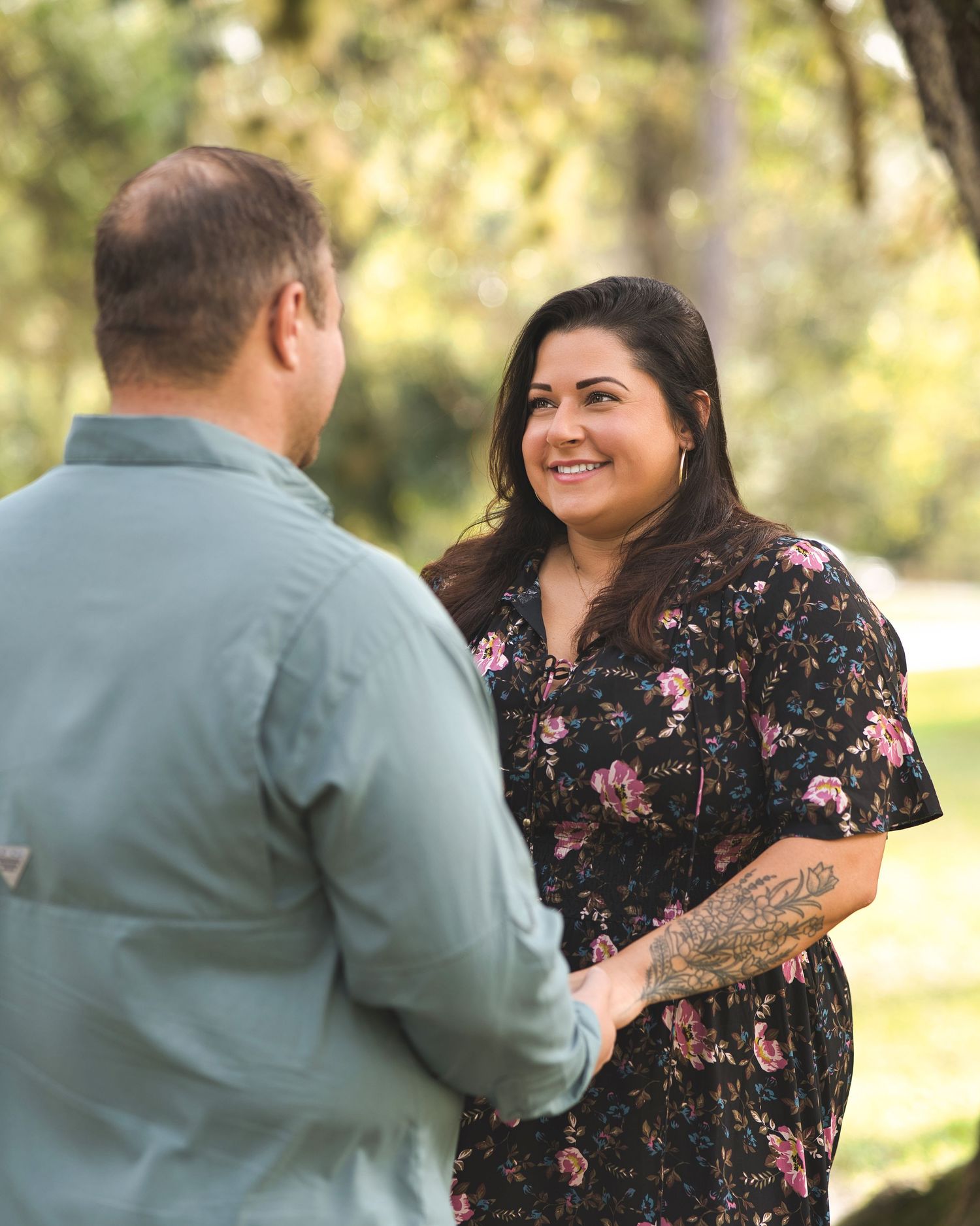 Couple holding hands and smiling at each other in an outdoor setting.