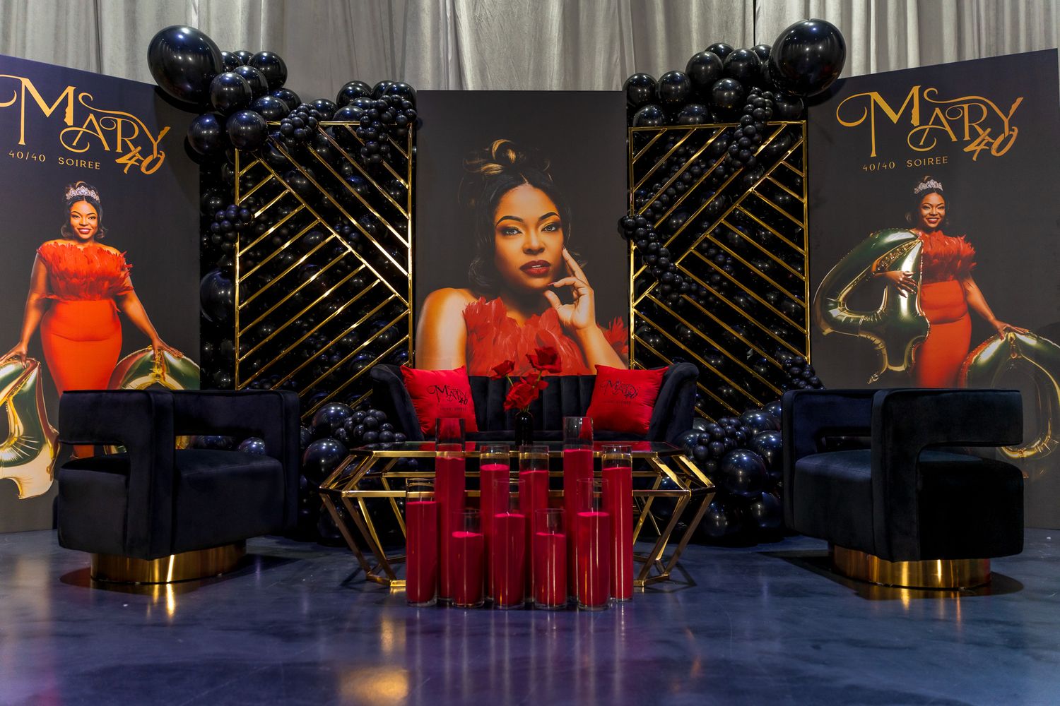 Event setup with red and black decor featuring illuminated posters and velvet chairs.