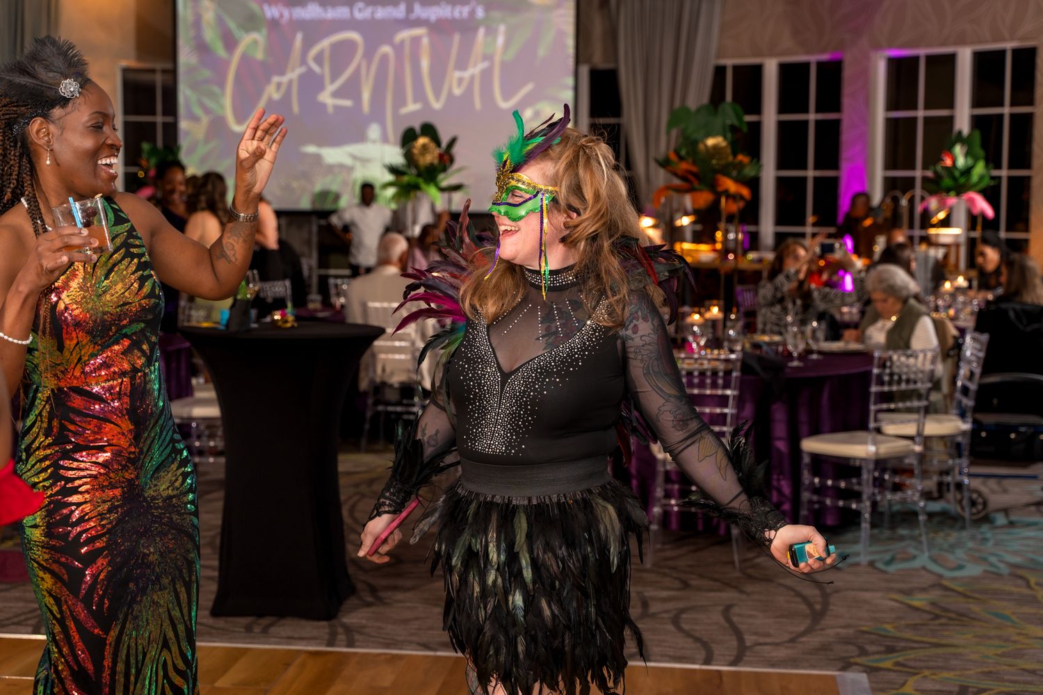 Guests in festive attire dancing and celebrating at an evening party with colorful decorative lighting.