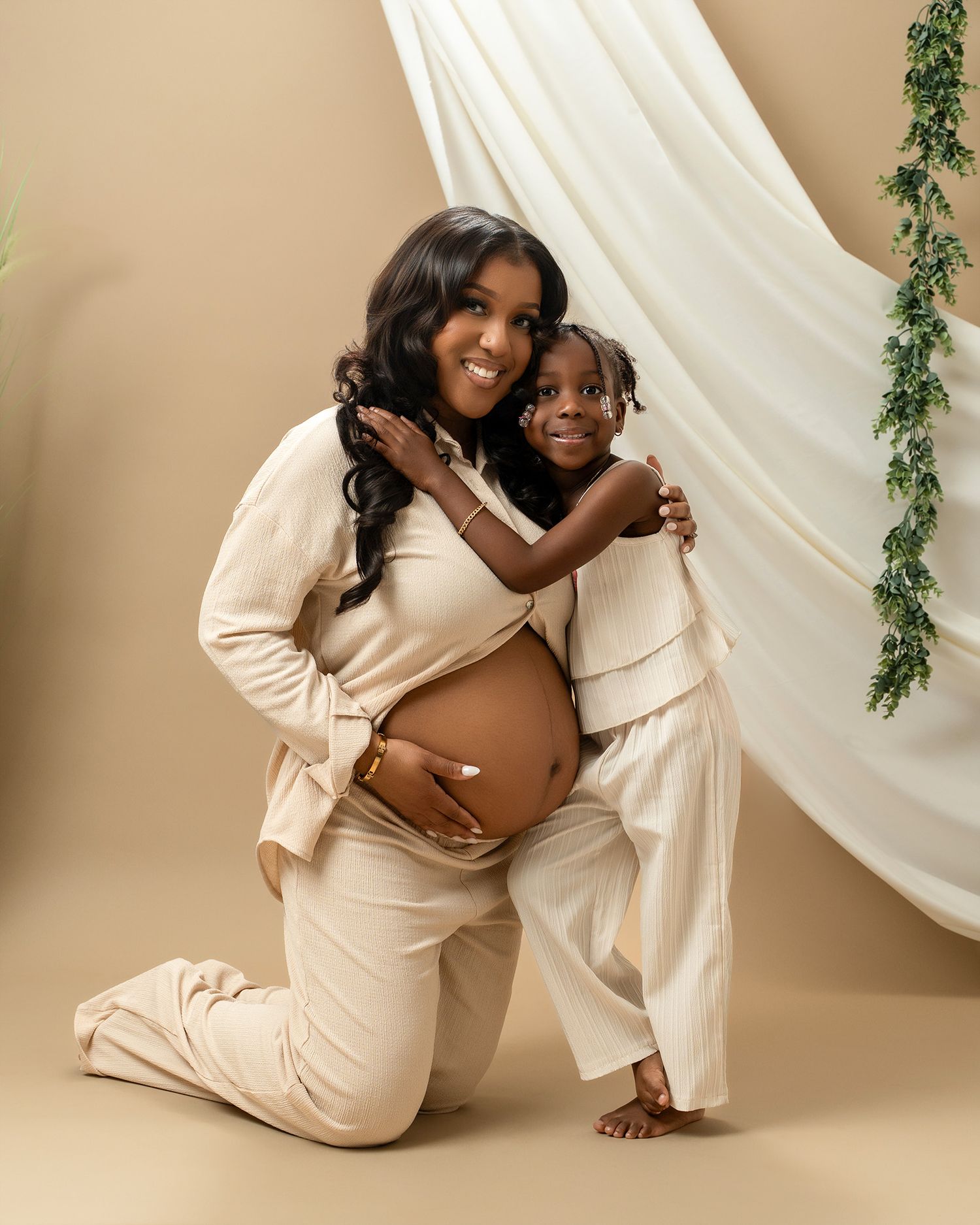 Mother and child share tender moment during maternity photoshoot in matching cream outfits.