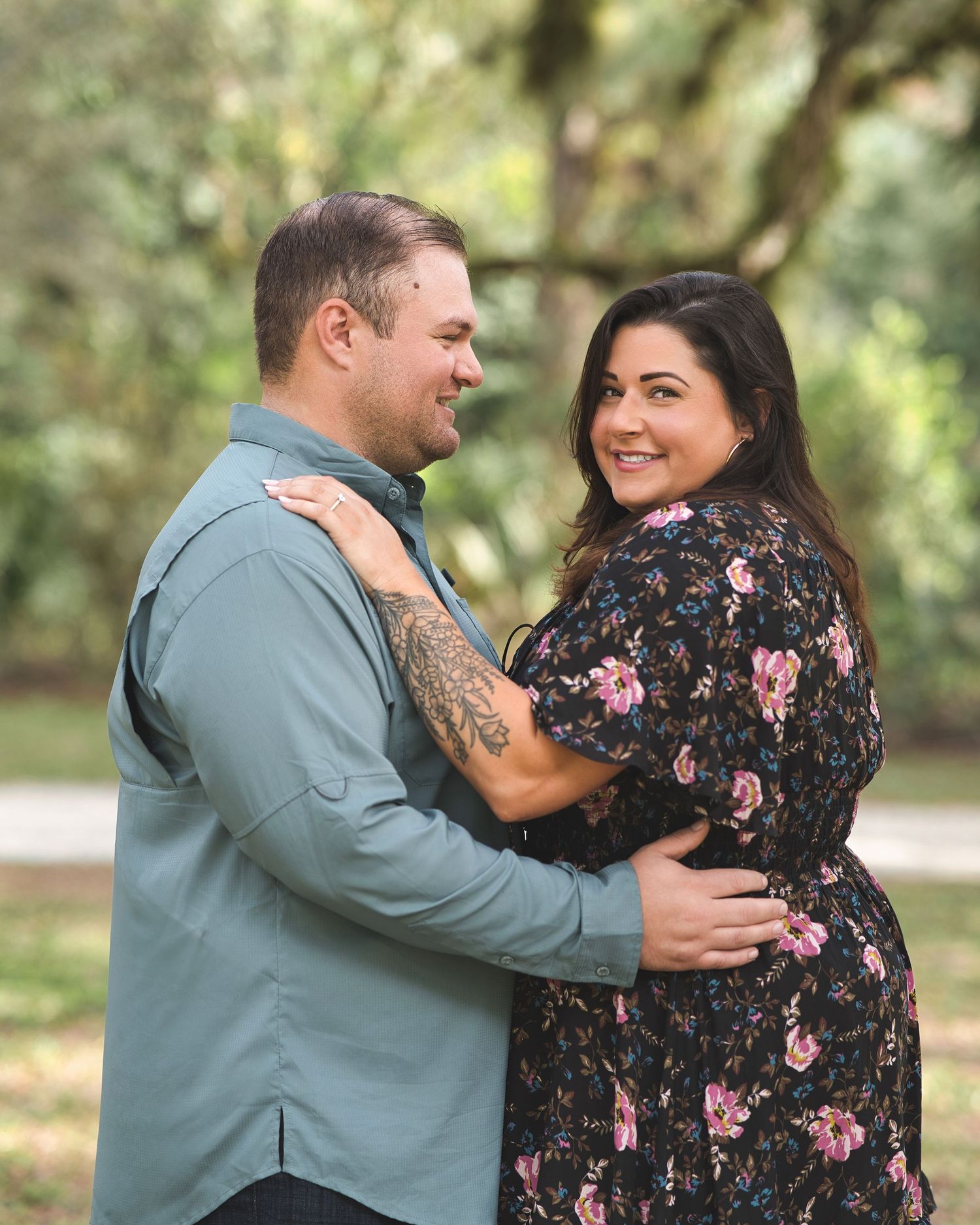 Romantic couple embracing and smiling at each other in a natural outdoor setting.