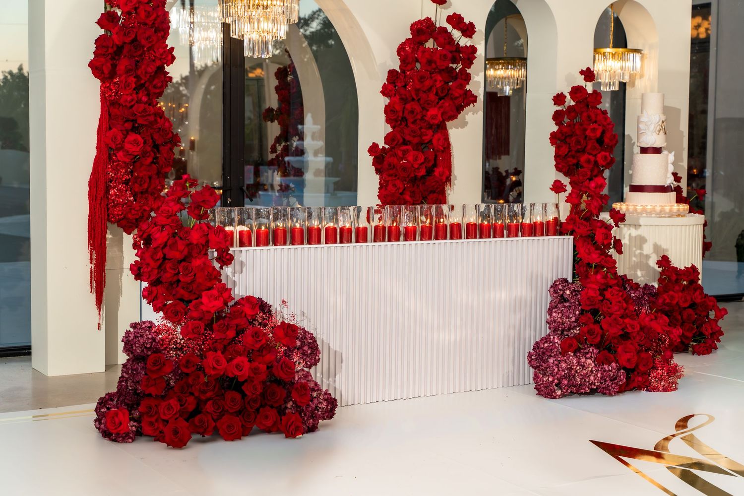 Interior hallway decorated with luxurious red rose arrangements along white arched walls.