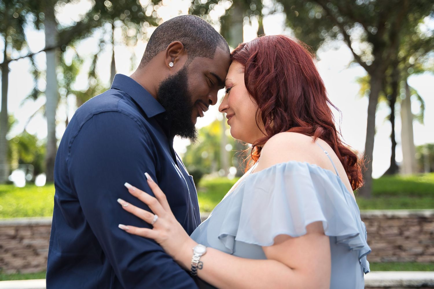 A romantic couple sharing an intimate moment outdoors in casual formal wear.