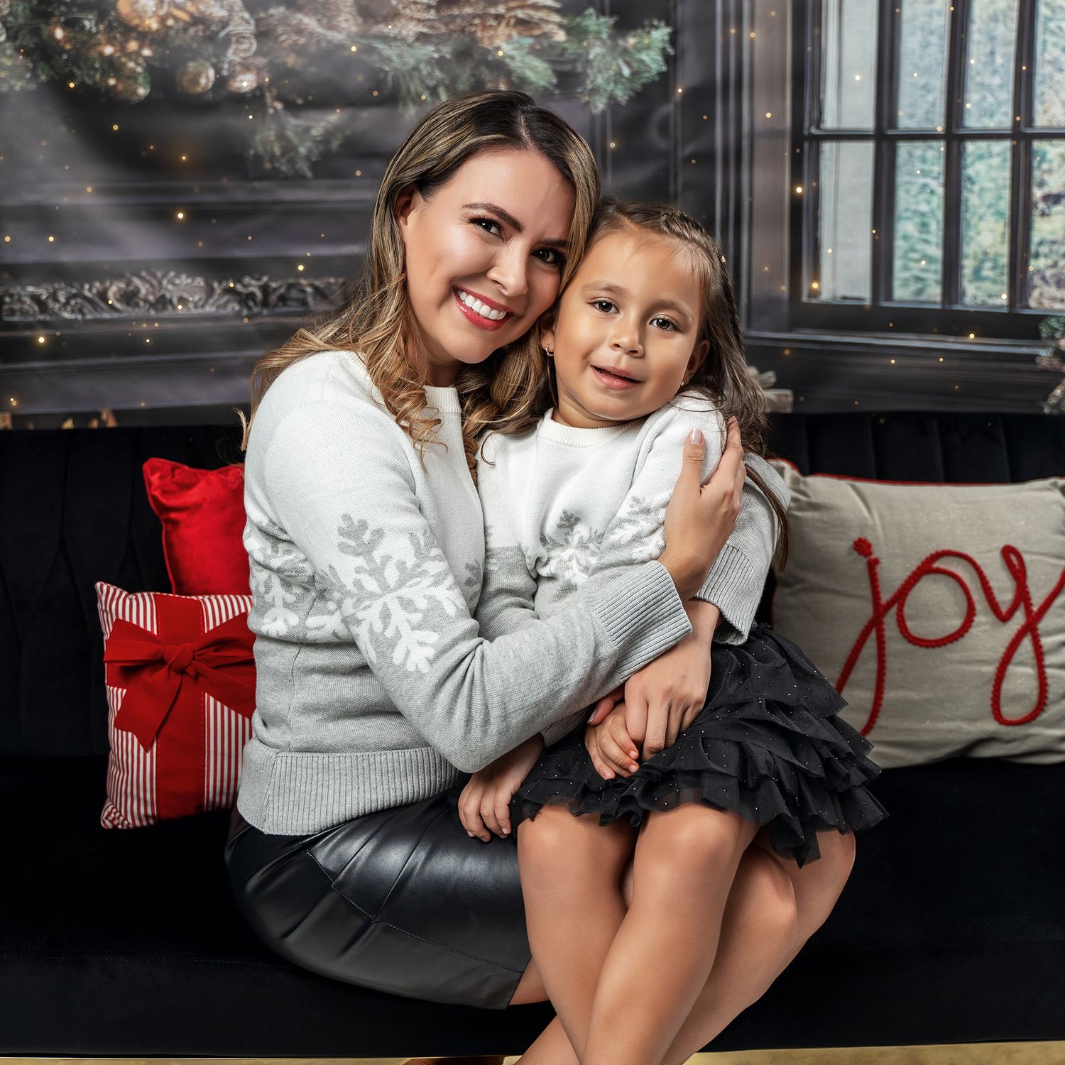 A warm embrace captured during a holiday photoshoot with matching winter sweaters and festive decorations.