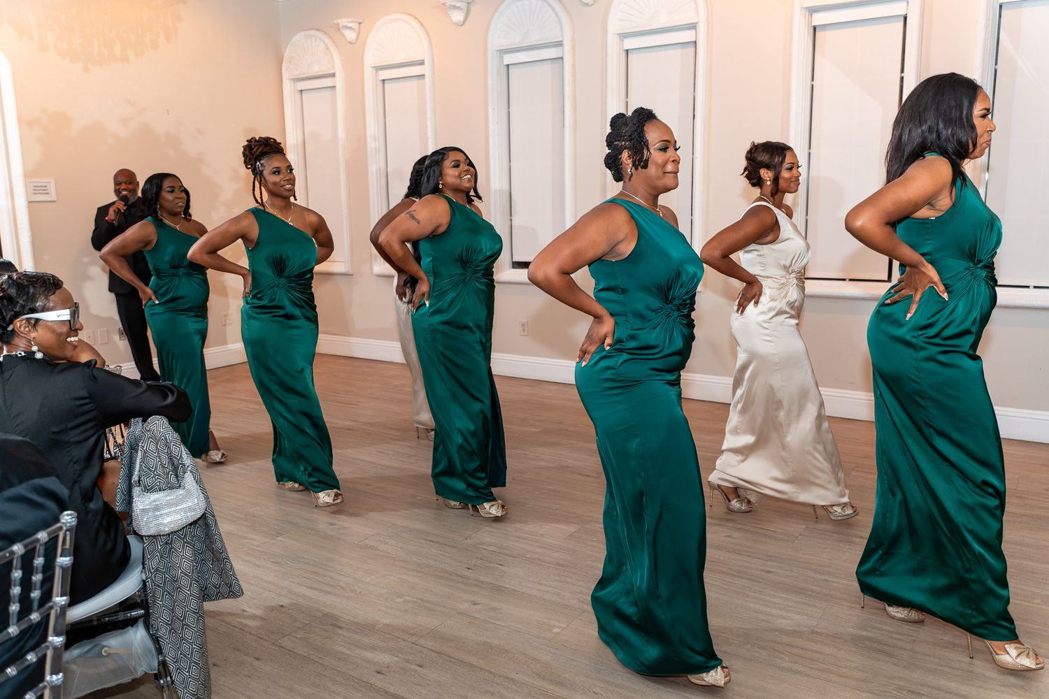 Bridesmaids in matching emerald green dresses performing a choreographed dance at a wedding reception.