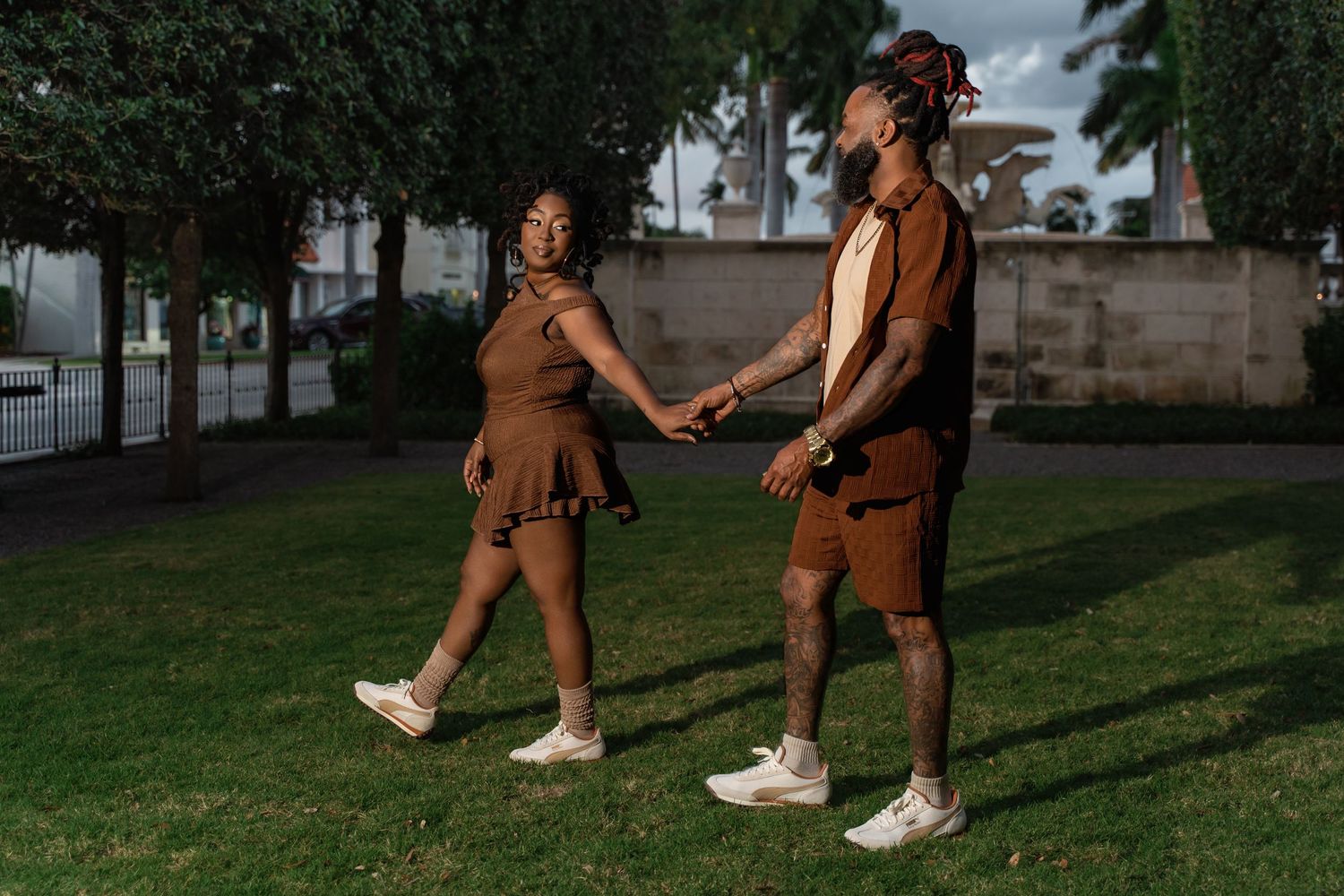 Two dancers perform a synchronized dance routine on a green lawn during an overcast day.