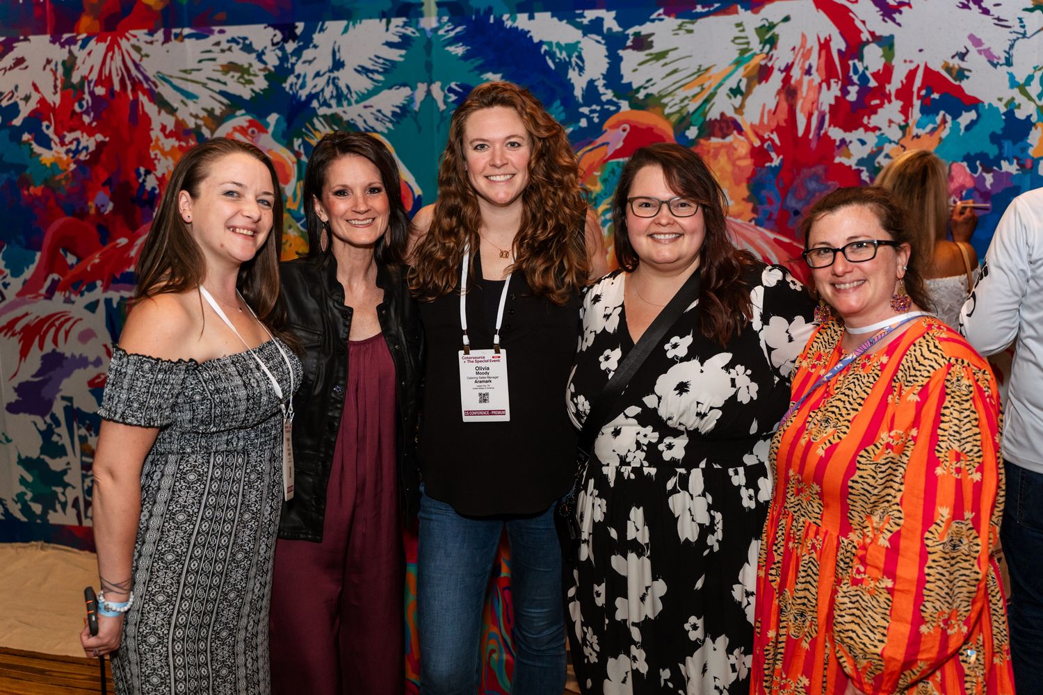 A group photo at an event with a colorful artistic backdrop featuring red and blue abstract patterns.