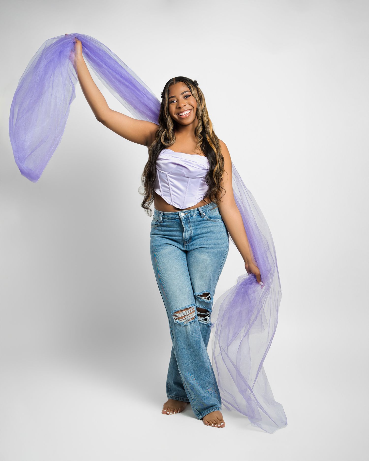 Dynamic pose with flowing purple fabric against white studio backdrop.