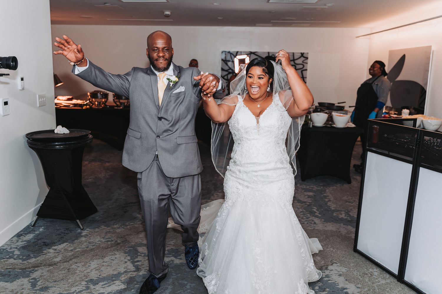 Joyful couple celebrates with raised arms during wedding reception.