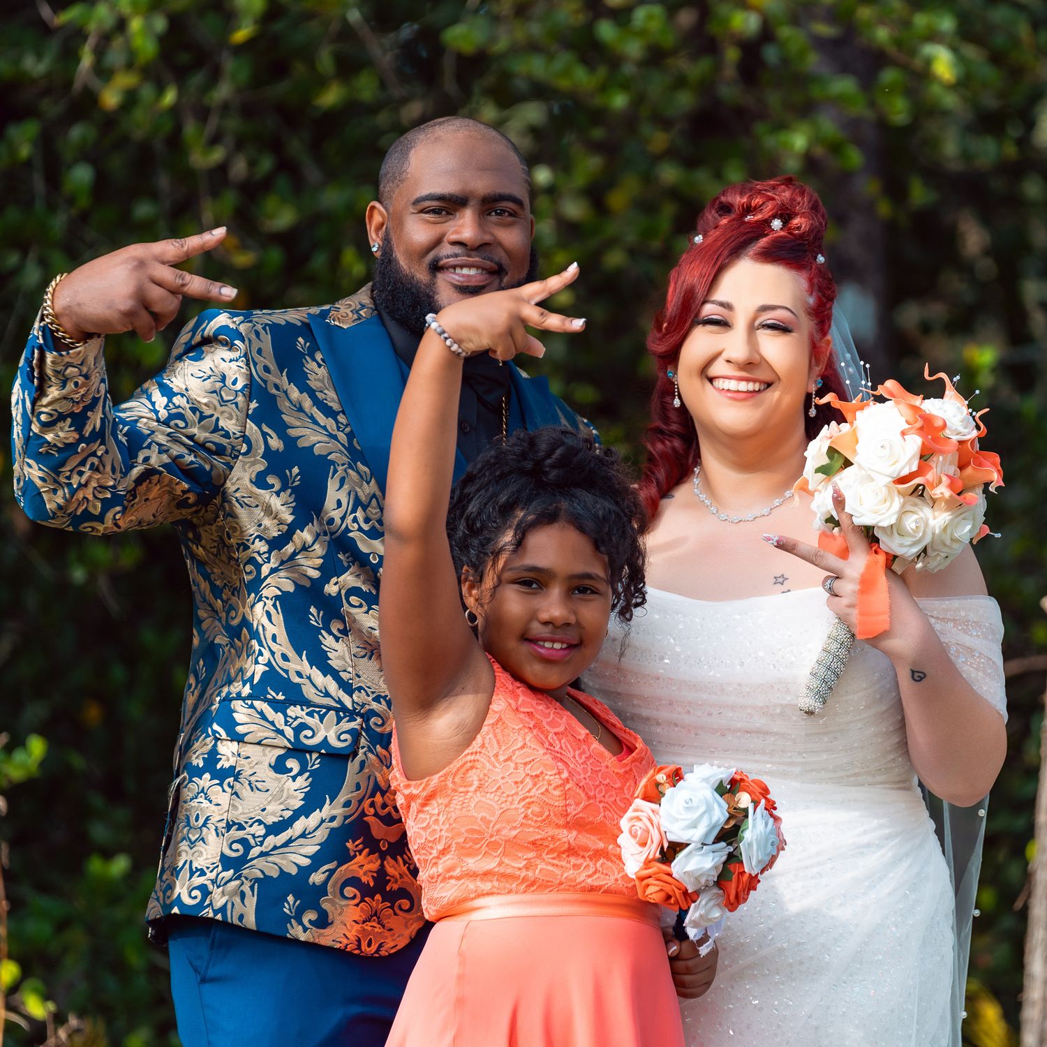 Wedding party poses joyfully outdoors with bright floral bouquets and vibrant attire.