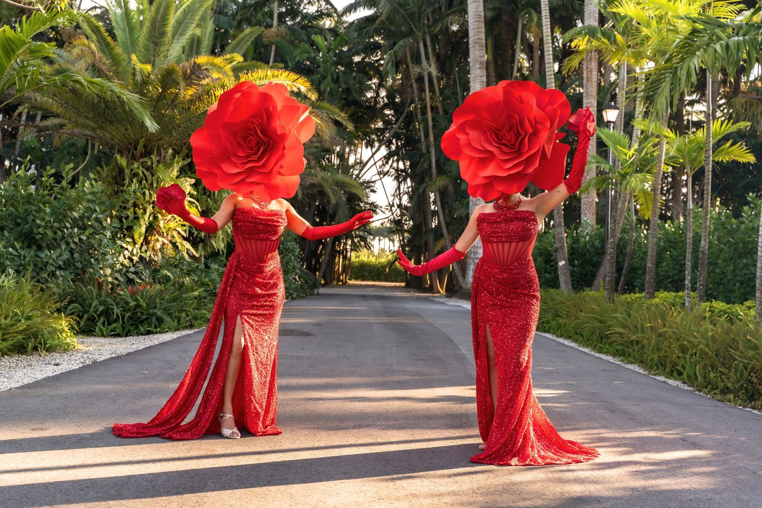 A person in a flowing red dress twirls gracefully through a tropical garden pathway.